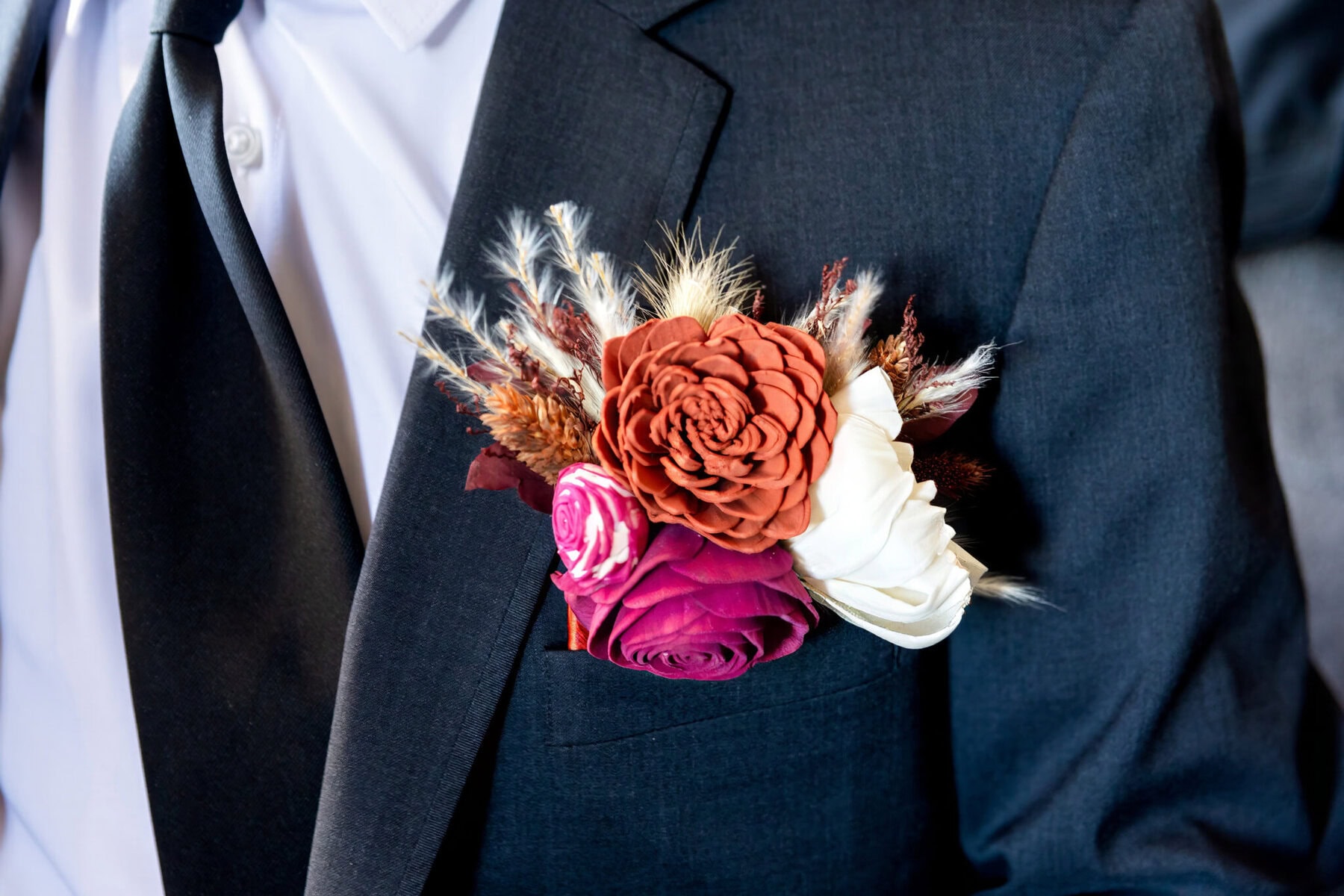 Wedding at the Newport Naval Station Officers' Club 25 A close-up of a suit jacket with a tie and wedding boutonniere, perfect for a Newport Naval Station Officers' Club celebration.