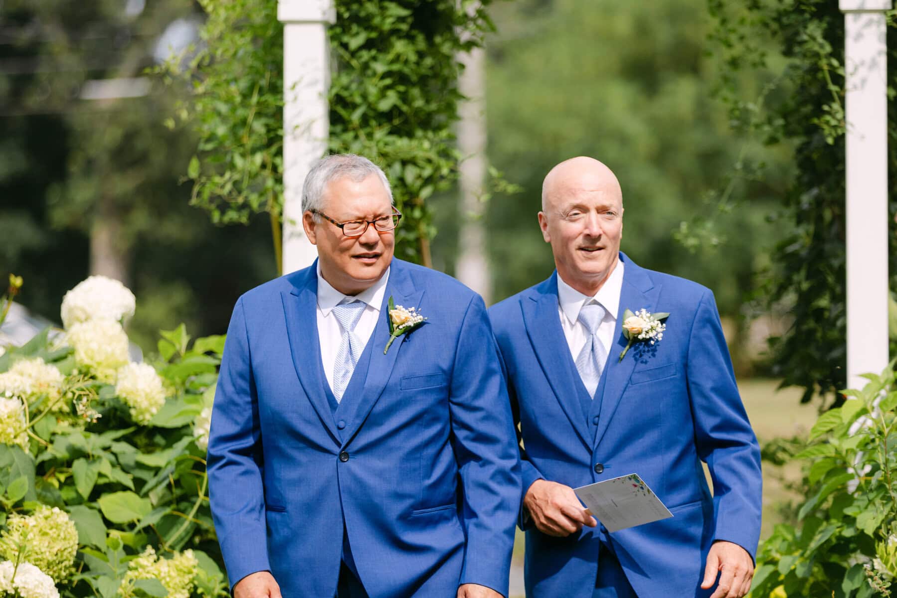 Wedding At the Holliston Historical Society 8 Two men in blue suits walking down a path at the Holliston Historical Society wedding venue.