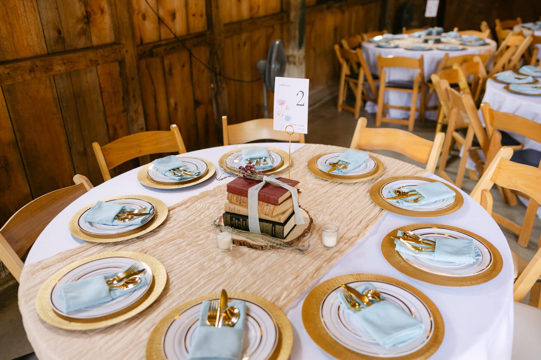 Wedding At the Holliston Historical Society 32 A round table set for six at a Holliston Historical Society wedding, with gold-rimmed plates and a bookish candle centerpiece.