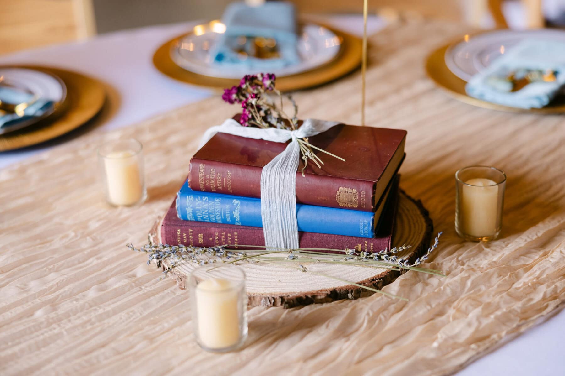 Wedding At the Holliston Historical Society 35 Three stacked books with white ribbon, dried flowers, and candles create a charming wedding centerpiece at Holliston Historical Society.