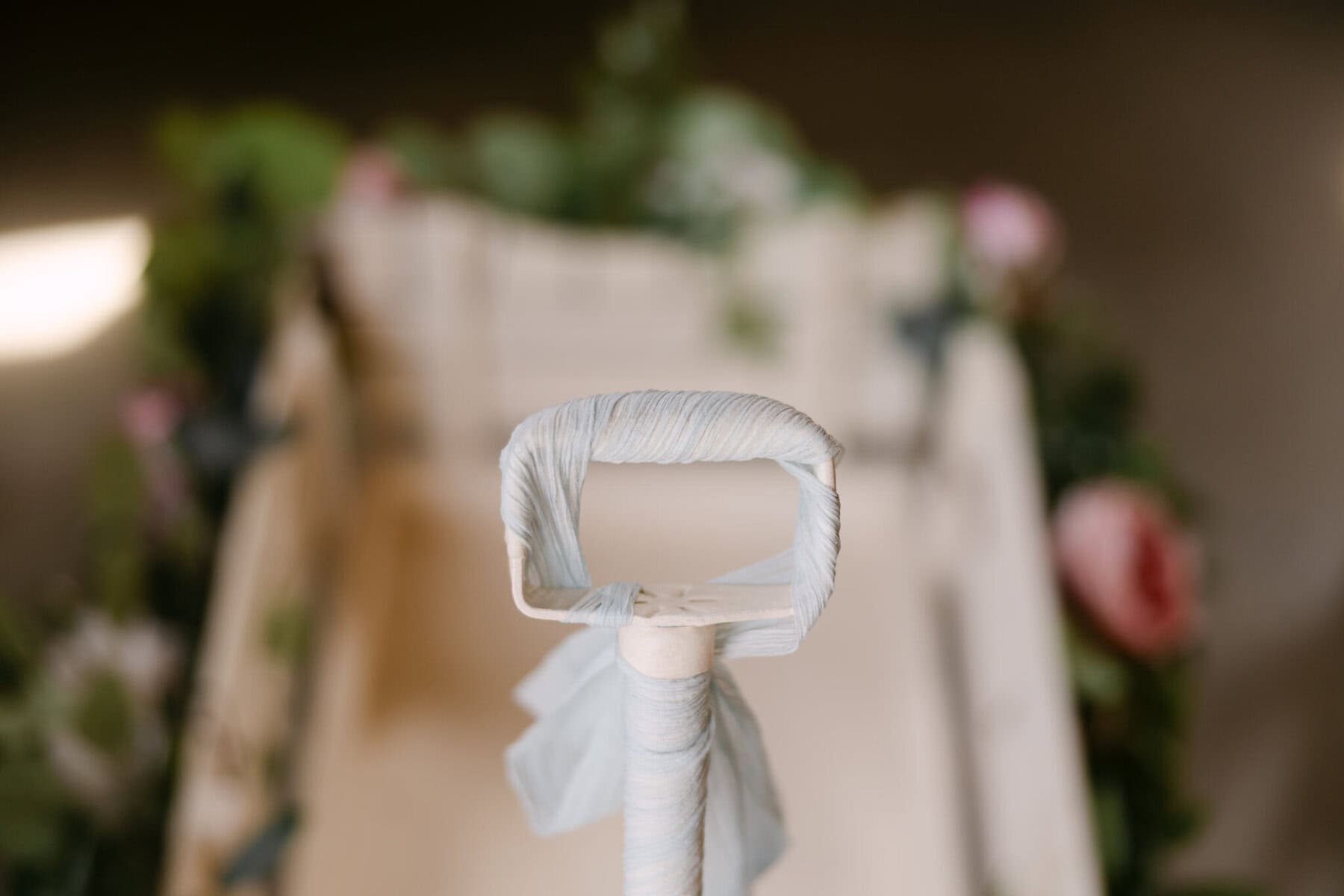 Wedding At the Holliston Historical Society 39 Close-up of a wagon handle at a Holliston Historical Society wedding, adorned with greenery and pink flowers in the background.