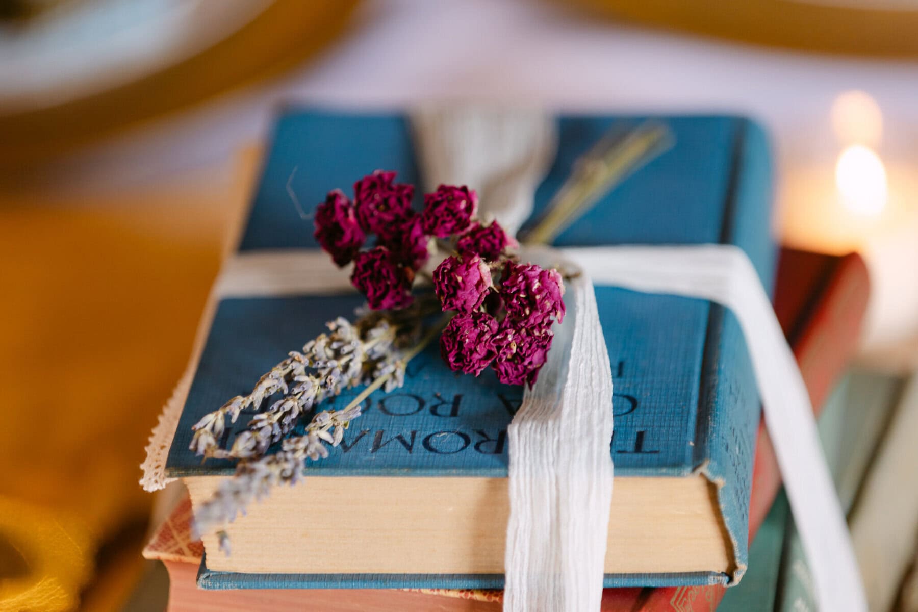 Wedding At the Holliston Historical Society 40 Stack of books tied with a white ribbon, topped with dried purple flowers—perfect for a Holliston Historical Society wedding décor.