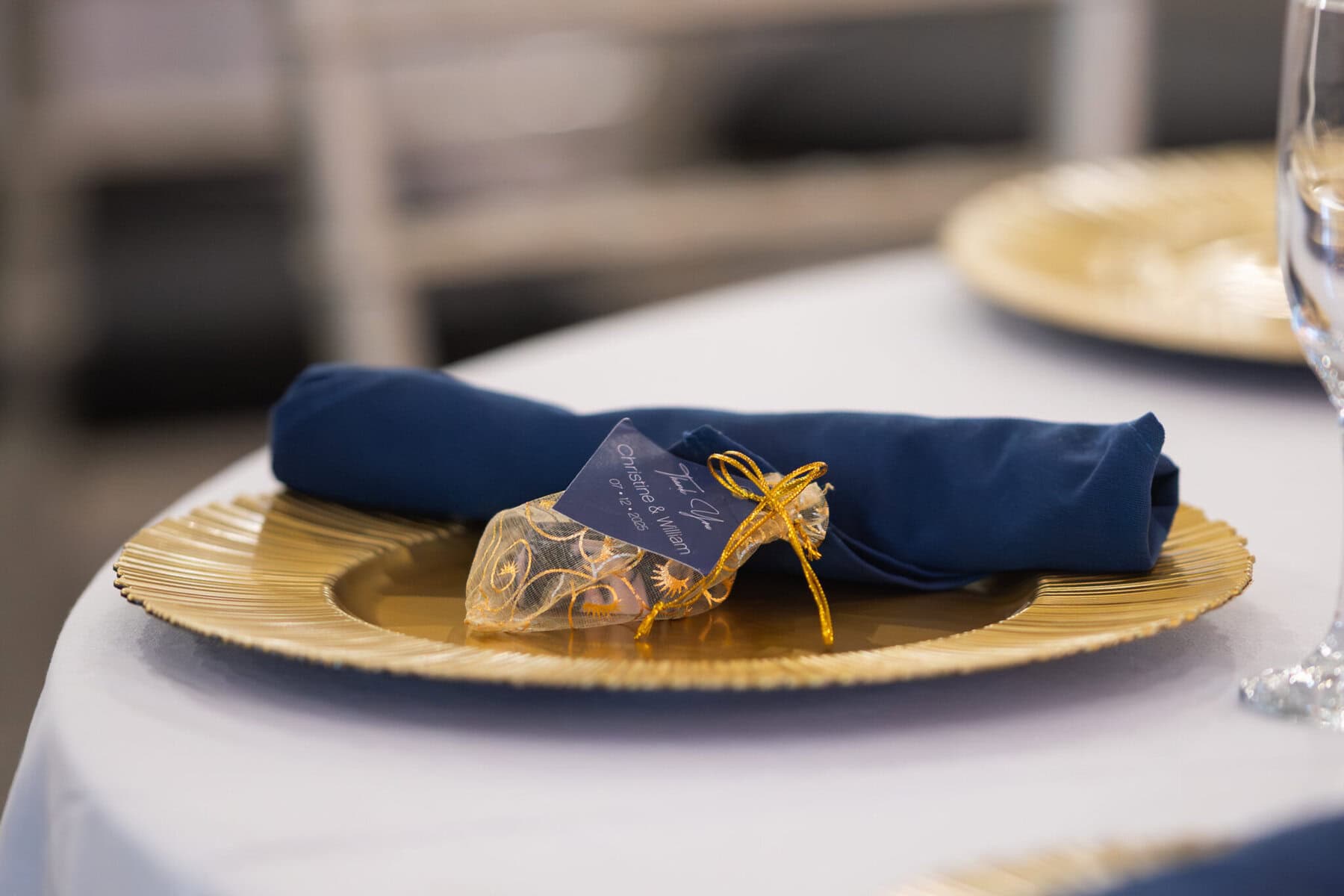 Stunning Wedding at Indian Ranch and Samuel Slater's Restaurant 66 A gold charger plate with a navy napkin and organza bag, perfect for a wedding at Samuel Slater's Restaurant.