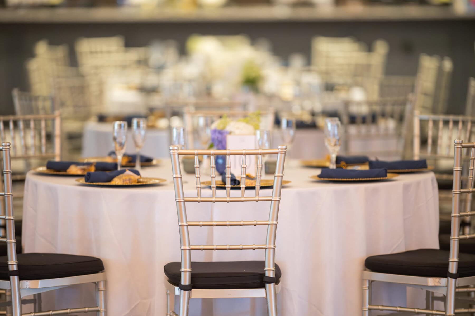Stunning Wedding at Indian Ranch and Samuel Slater's Restaurant 67 Round table with a white tablecloth, silver chairs, and navy napkins set for a formal wedding at Samuel Slater's Restaurant.