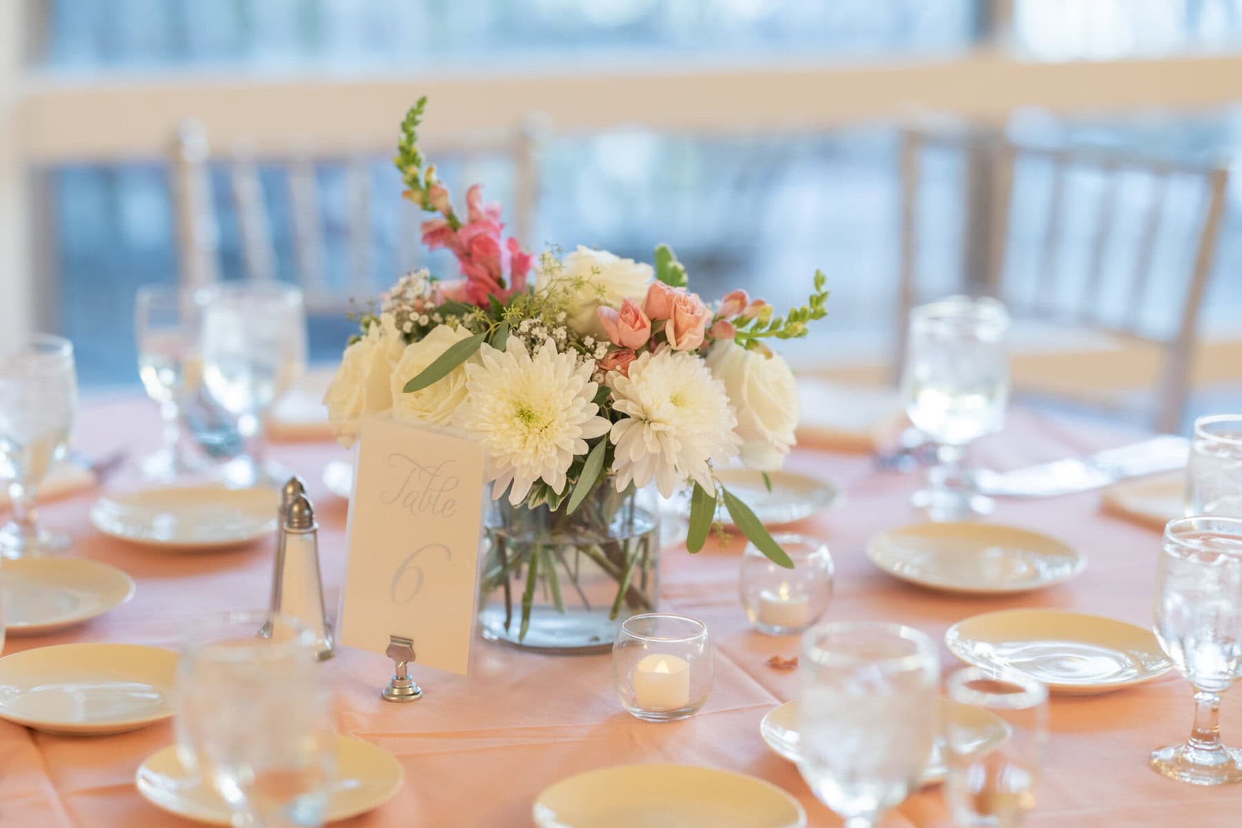 Beautiful Lake Pearl Wedding in Wrentham, MA 21 Round table with a pink tablecloth, floral centerpiece, and candles set for a formal Lake Pearl Wedding in Wrentham MA.