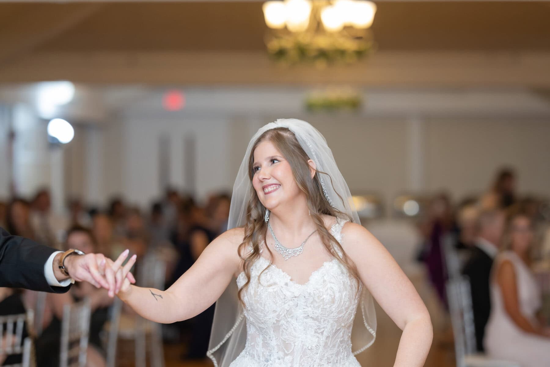 Beautiful Lake Pearl Wedding in Wrentham, MA 35 A bride in a white wedding dress and veil smiles while holding hands at a beautiful Lake Pearl Wedding in Wrentham MA.