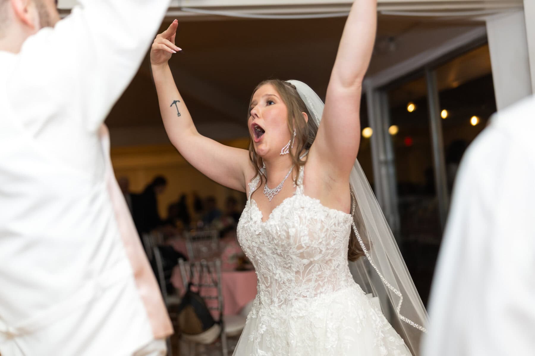 Beautiful Lake Pearl Wedding in Wrentham, MA 43 A bride in a white lace dress and veil celebrates indoors at her Lake Pearl Wedding in Wrentham MA.