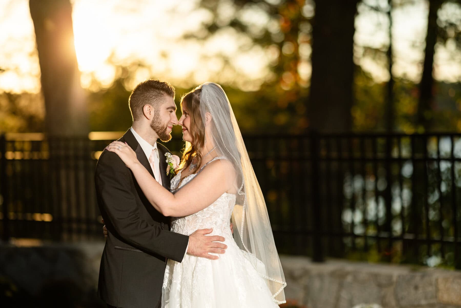 Beautiful Lake Pearl Wedding in Wrentham, MA 5 A bride and groom embrace outdoors at their Lake Pearl Wedding, with trees and sunlight illuminating the Wrentham MA backdrop.