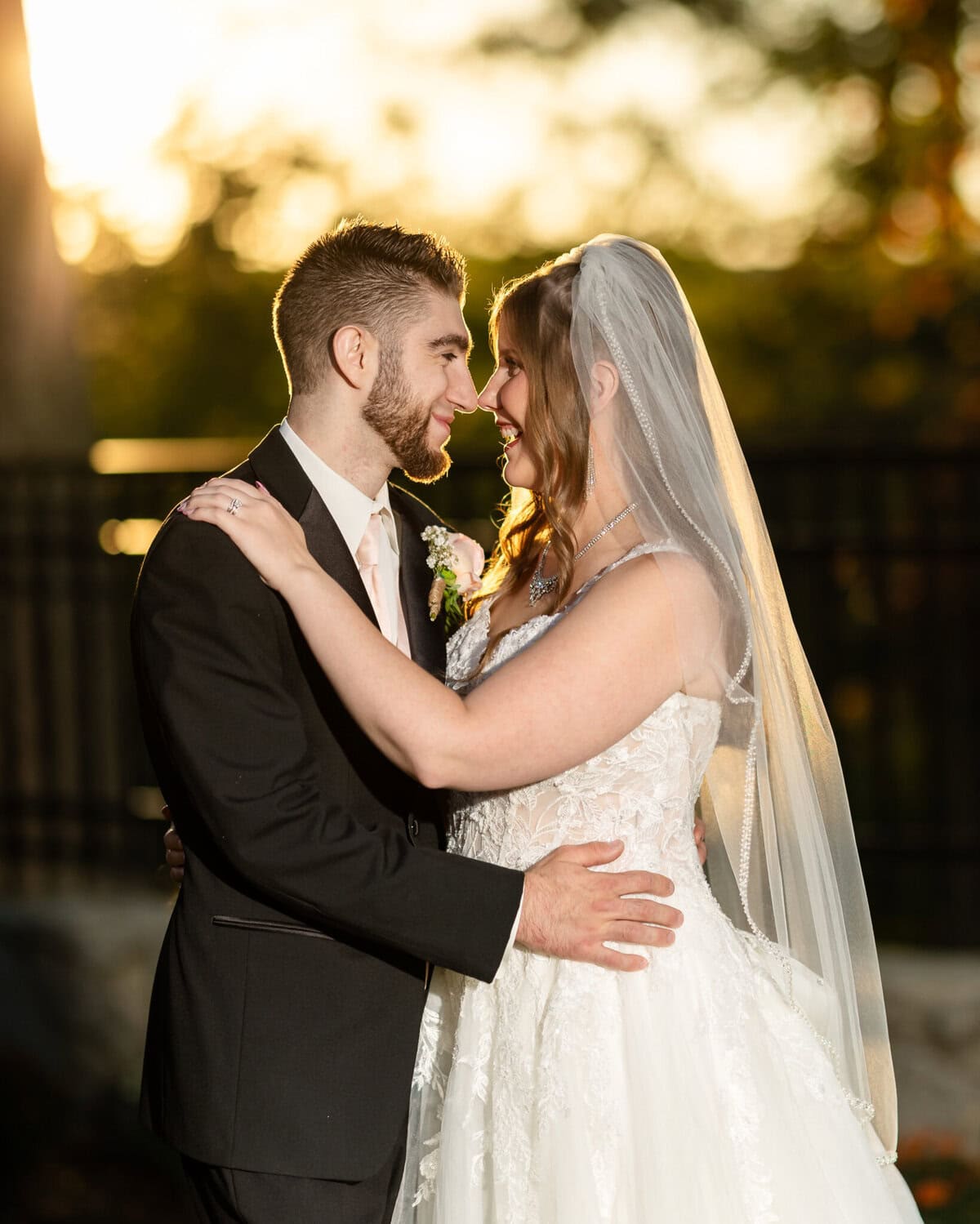Beautiful Lake Pearl Wedding in Wrentham, MA 6 A bride and groom in wedding attire embrace and smile at each other outdoors at sunset during their Lake Pearl Wedding in Wrentham, MA.