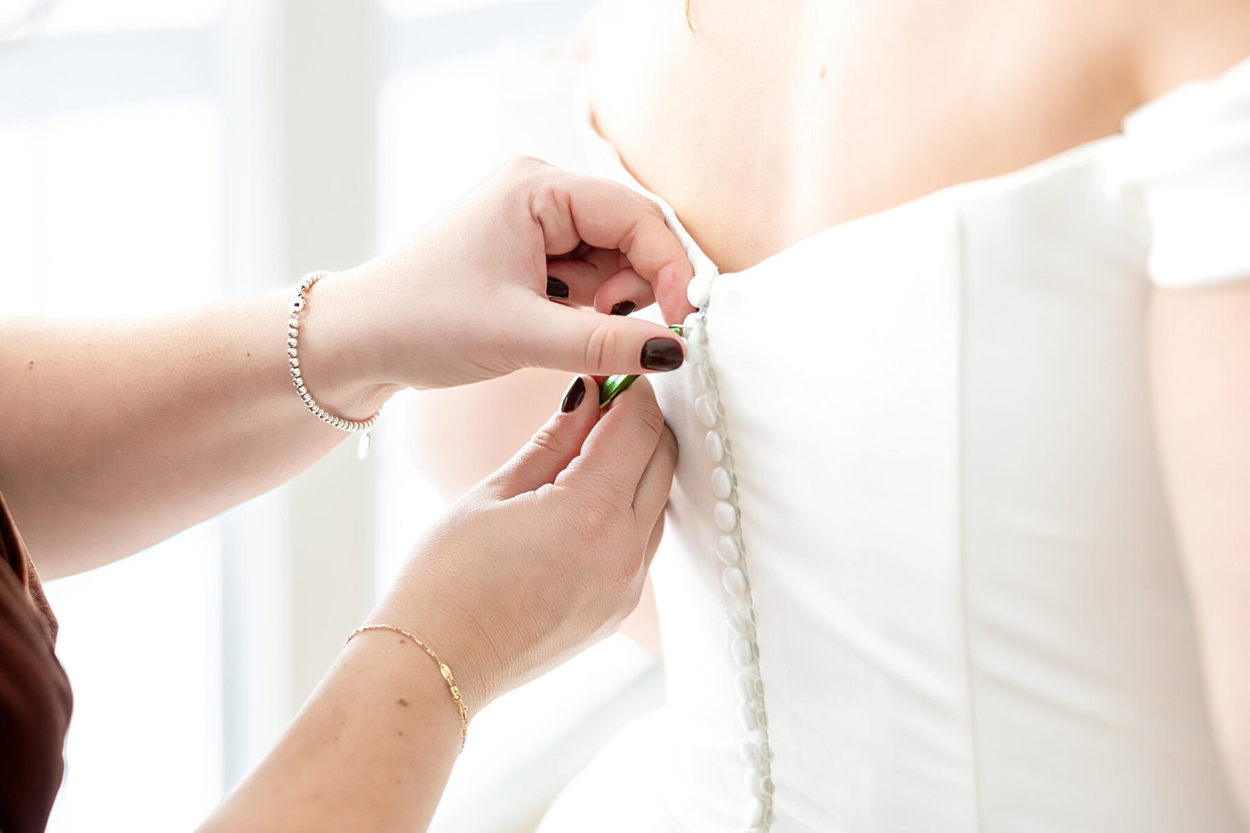 Wedding at the Newport Naval Station Officers' Club 6 A person's hands buttoning a wedding dress at the Newport Naval Station Officers' Club.