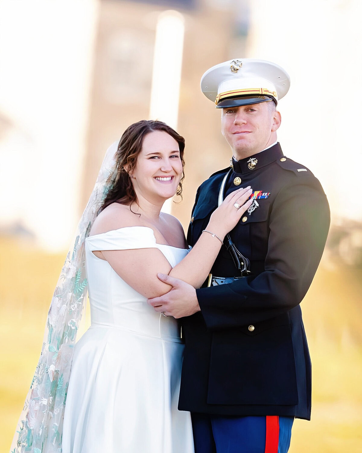 Wedding at the Newport Naval Station Officers' Club 45 A bride in white and a groom in uniform smile outdoors at Newport Naval Station, celebrating their wedding at the Officers' Club.