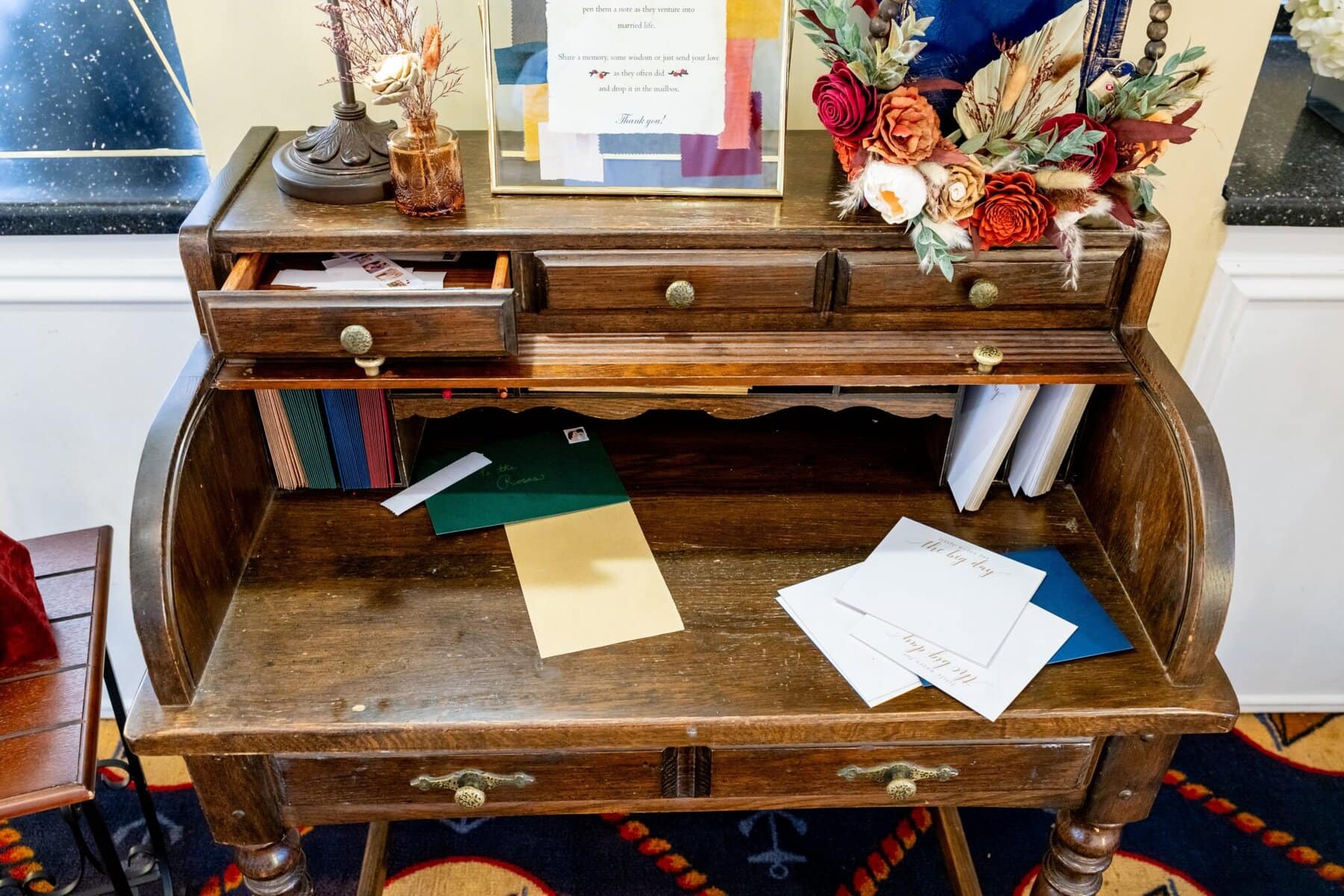 Wedding at the Newport Naval Station Officers' Club 74 A wooden writing desk at the Officers' Club, Newport Naval Station, with open drawers, papers, books, and a floral arrangement on top.