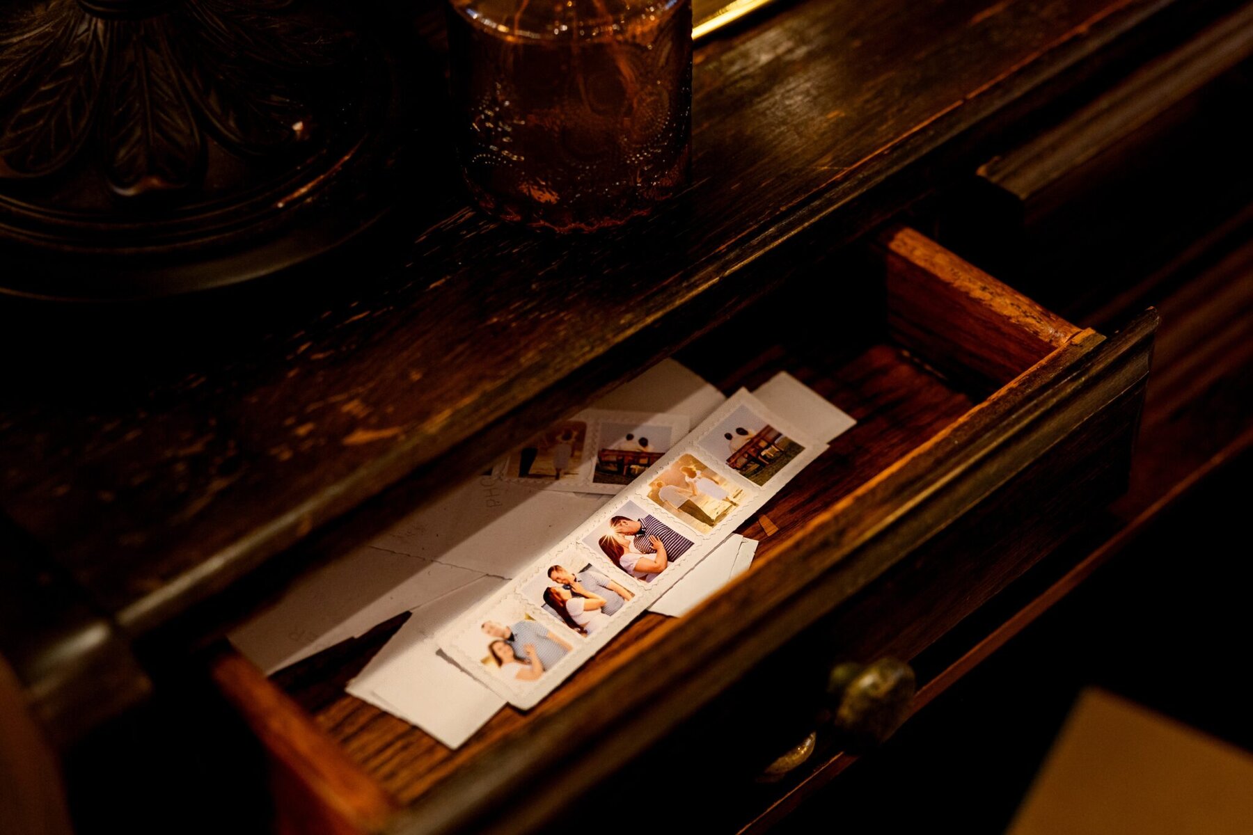 Wedding at the Newport Naval Station Officers' Club 76 An open wooden drawer holds papers and photo booth pictures from a wedding at the Officers' Club, Newport Naval Station; a tumbler sits above.