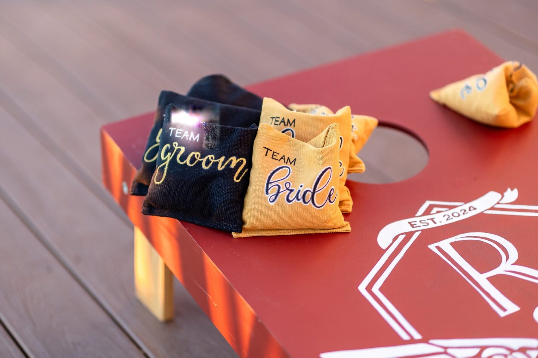 Wedding at the Newport Naval Station Officers' Club 78 Two bean bags labeled "Team Groom" and "Team Bride" rest on a wedding cornhole board at Newport Naval Station Officers' Club.
