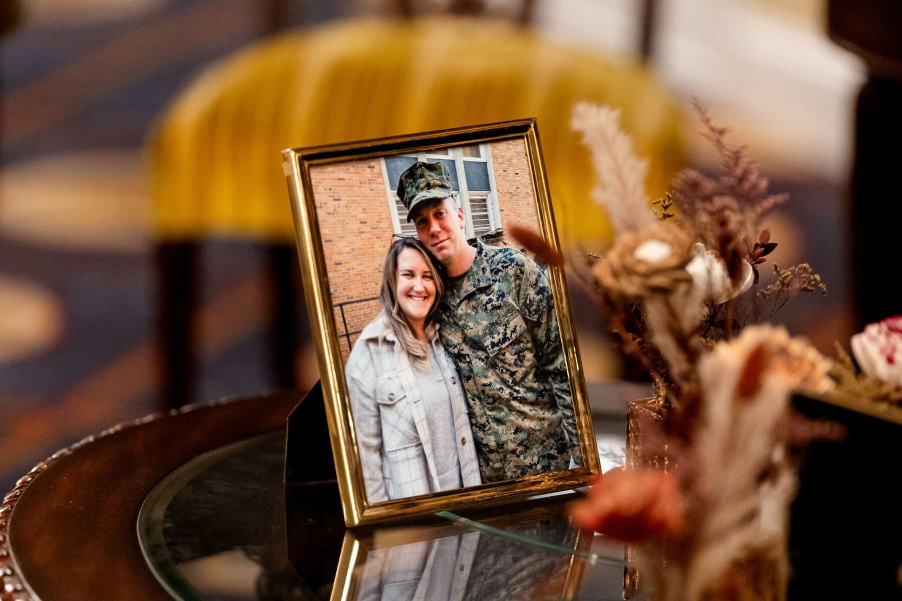 Wedding at the Newport Naval Station Officers' Club 80 A framed photo of a man in military uniform and a woman at their wedding, displayed on a table with dried flowers nearby.