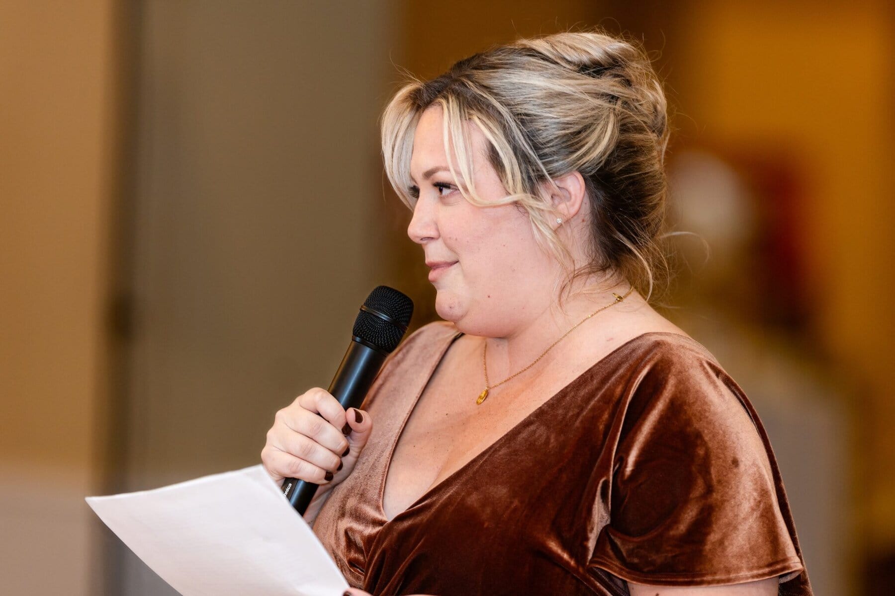 Wedding at the Newport Naval Station Officers' Club 84 A woman in a brown velvet dress holds a microphone and paper, speaking indoors at the Newport Naval Station Officers' Club wedding.