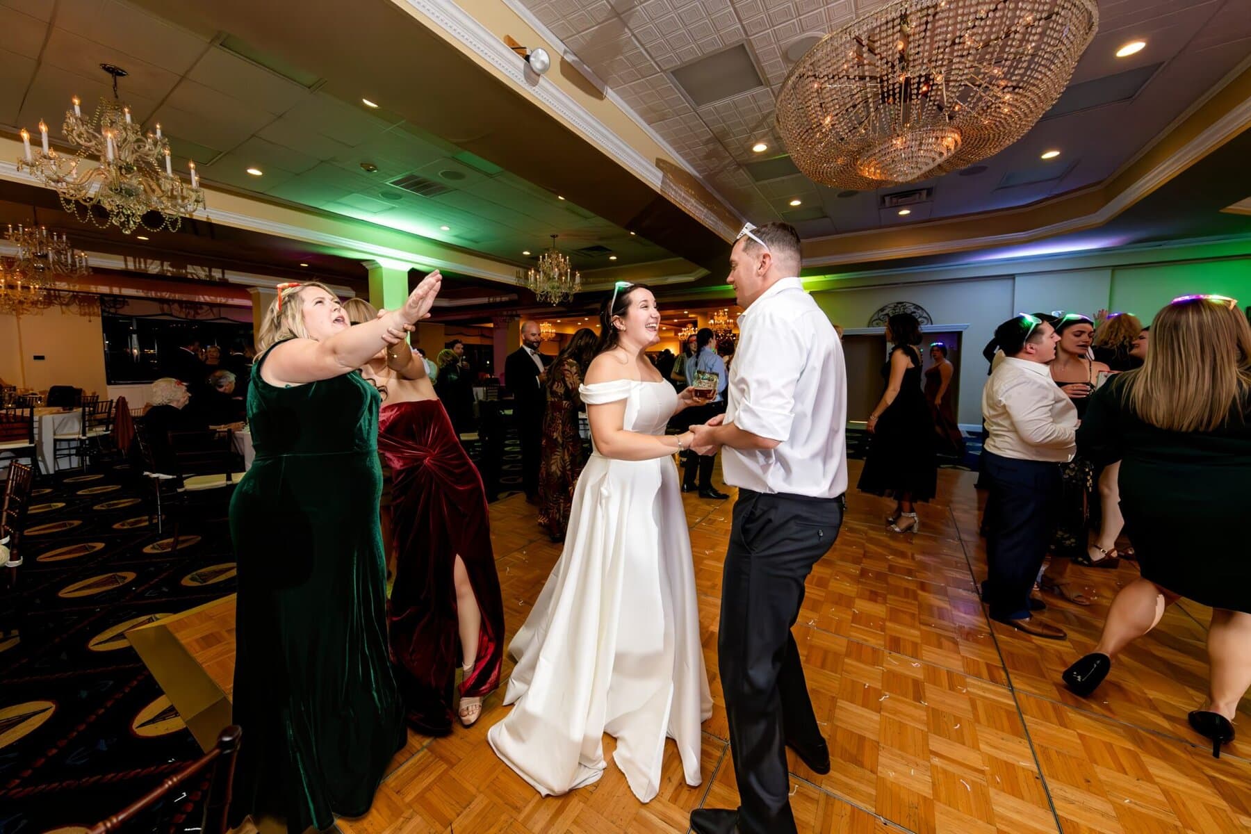 Wedding at the Newport Naval Station Officers' Club 93 A bride in a white dress dances with a man on the parquet floor at an Officers' Club wedding as guests in formal attire celebrate around them.