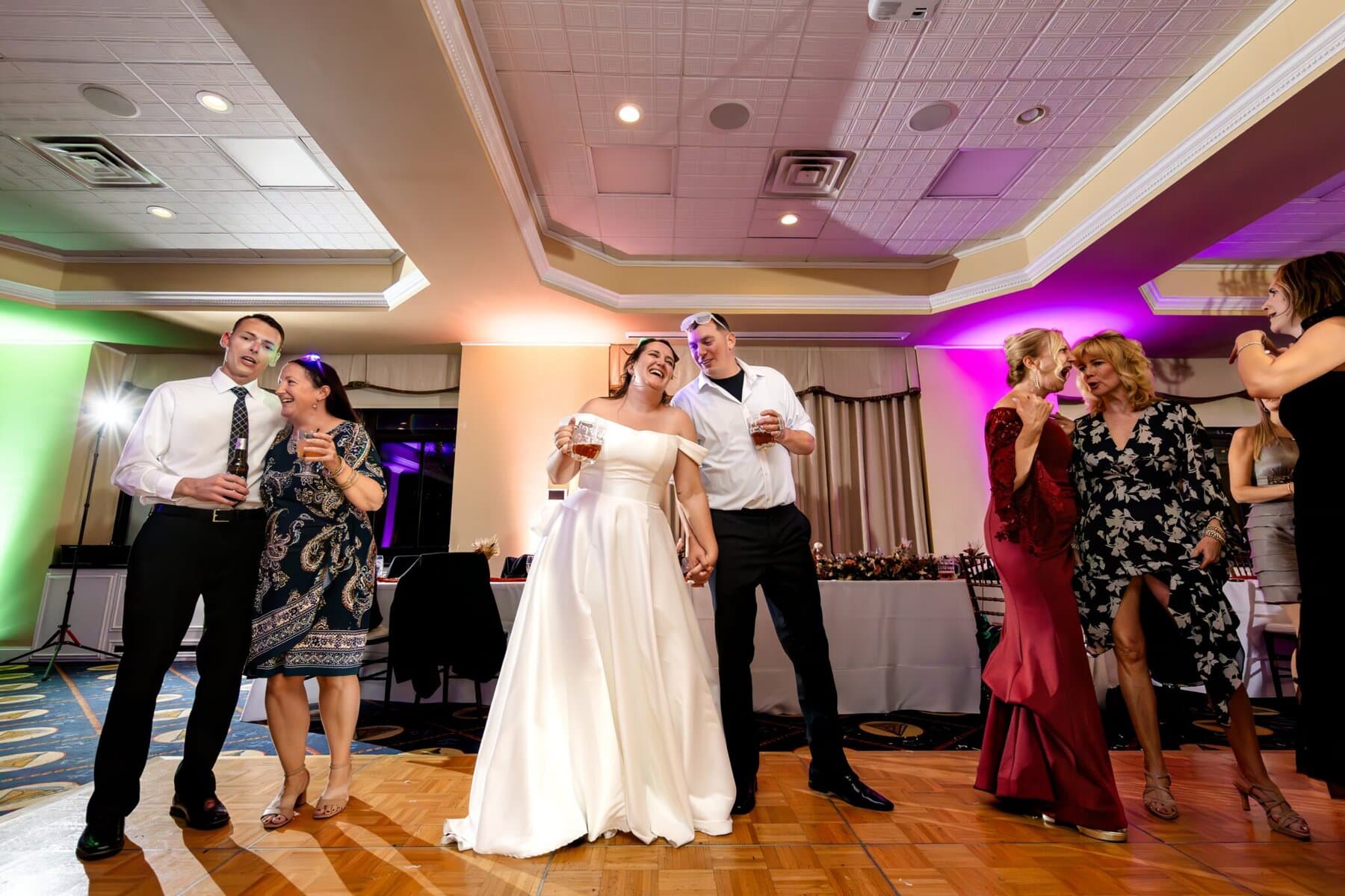 Wedding at the Newport Naval Station Officers' Club 95 A bride and groom laugh together on the dance floor at a Newport Naval Station wedding, surrounded by guests at the Officers' Club.