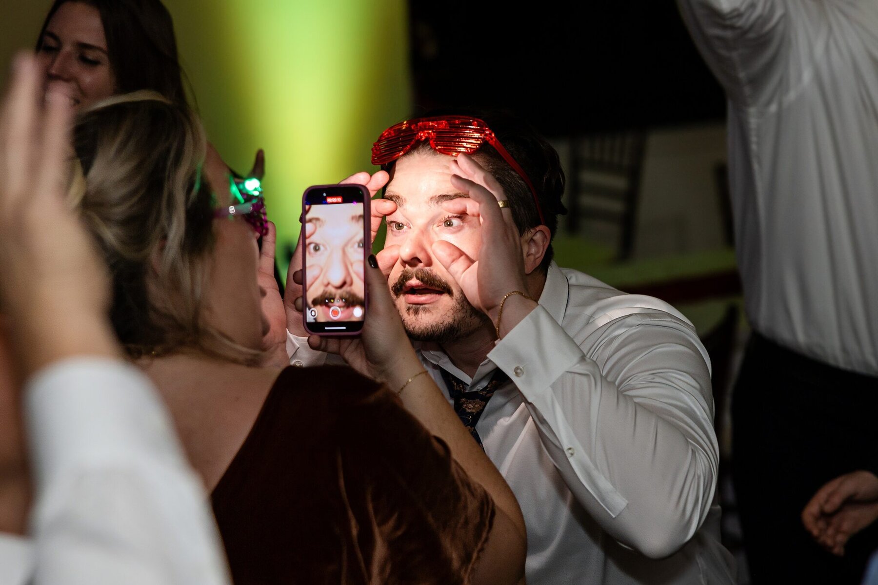 Wedding at the Newport Naval Station Officers' Club 104 A man holds his eyes open as a woman snaps a close-up at a wedding party at the Officers' Club, Newport Naval Station.
