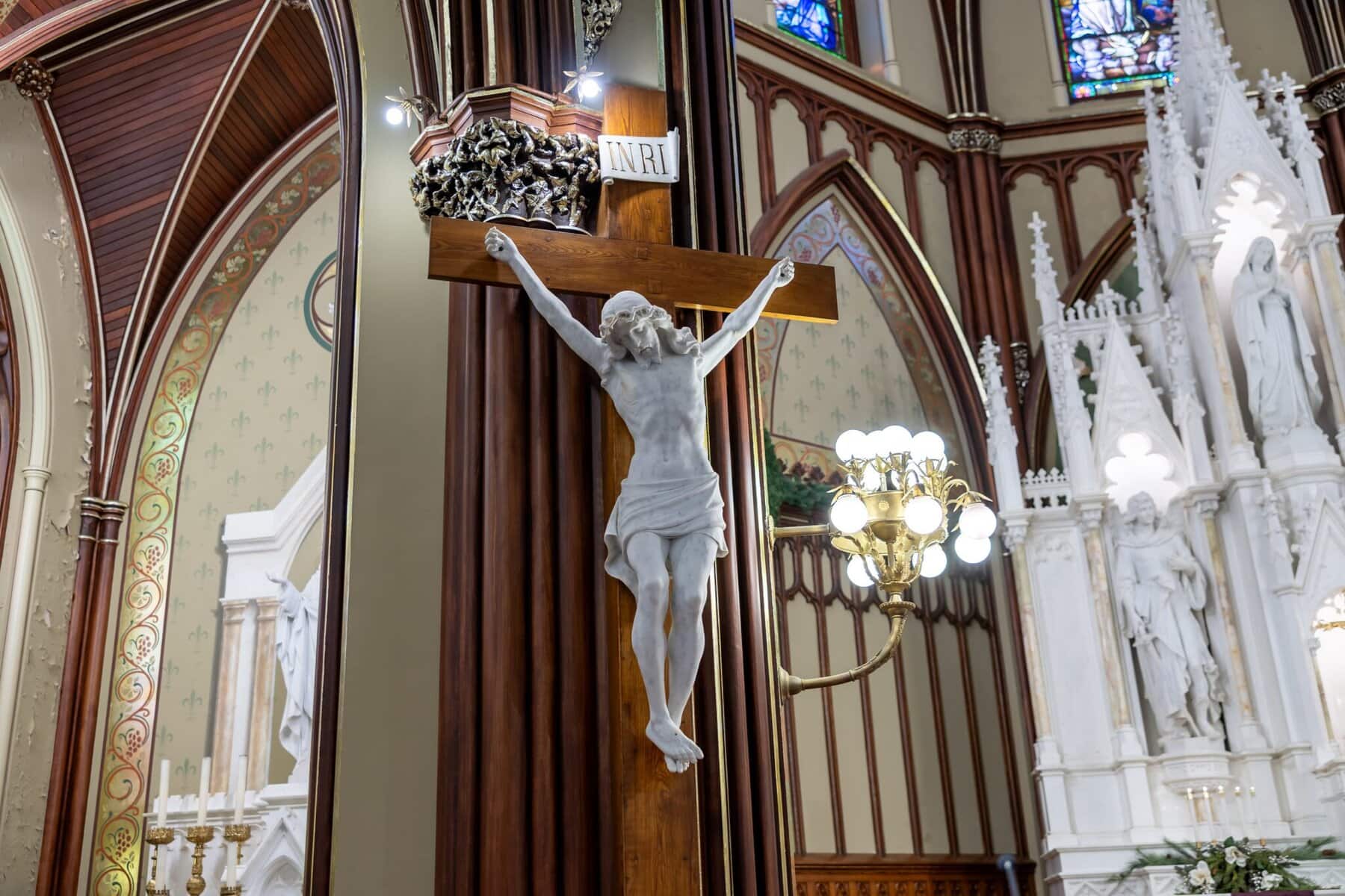 Wedding At the Transfiguration of the Lord Parish 8 A crucifix with Jesus stands on a wooden pillar inside an ornate church, ideal as a wedding venue with stained glass and decorative details.
