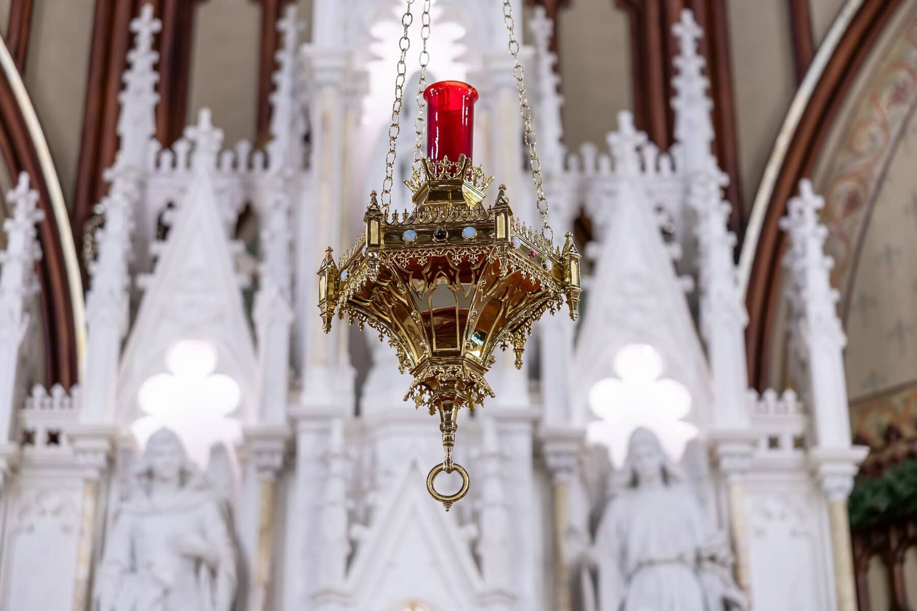Wedding At the Transfiguration of the Lord Parish 9 A gold sanctuary lamp with a red glass top hangs before the ornate altar, honoring the Transfiguration of the Lord and wedding celebrations.
