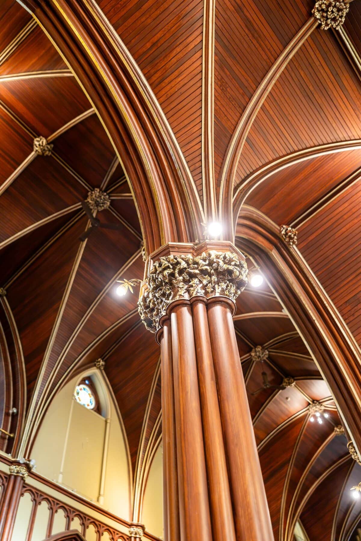 Wedding At the Transfiguration of the Lord Parish 17 Close-up of a tall, ornate wooden column with gold detailing in a cathedral, perfect for a Wedding or the Transfiguration of the Lord celebration.