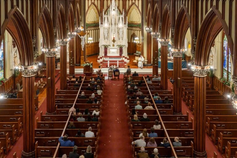 A view from above of a wedding at Transfiguration of the Lord Parish, with guests seated in pews facing the altar during the ceremony.