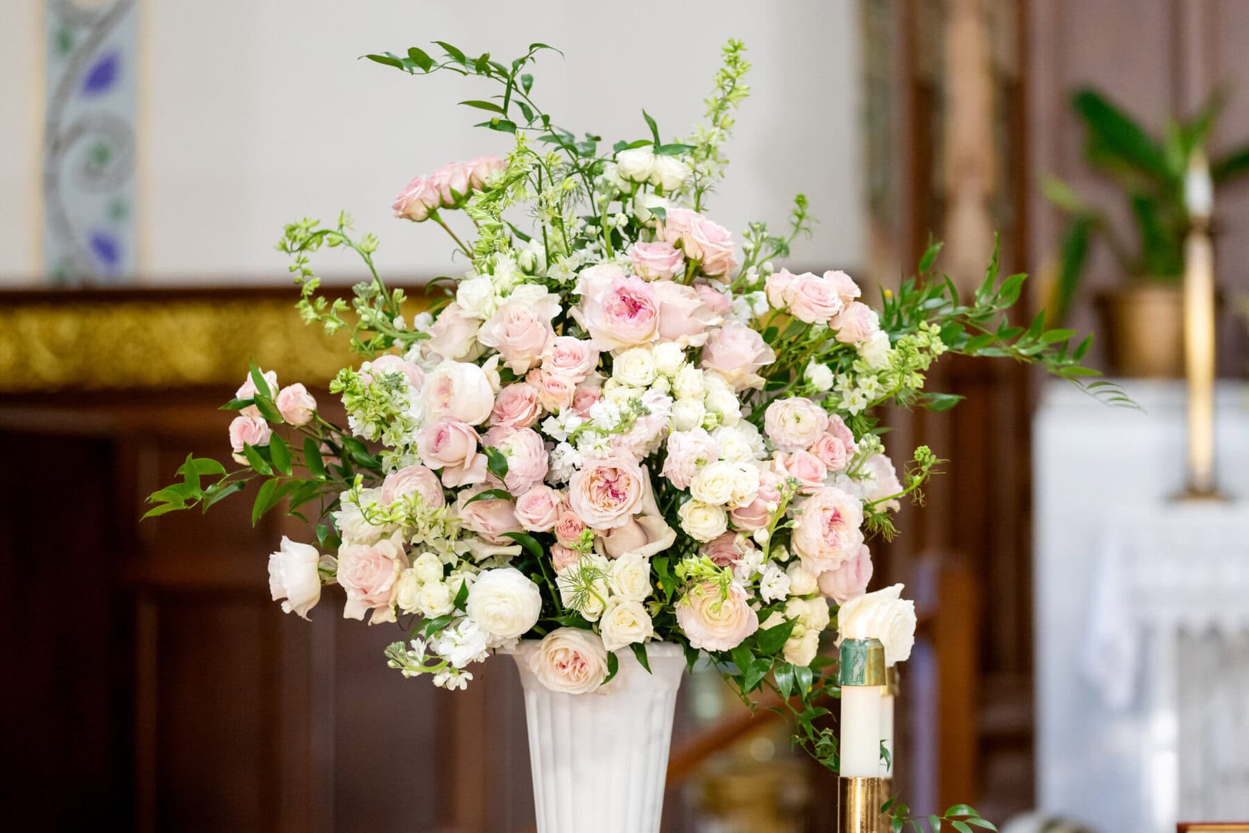 Wedding At Santo Christo Parish in Fall River 9 A tall white vase filled with pink and white roses and greenery, perfect for a Wedding at Santo Christo Parish in Fall River, on a wooden surface.