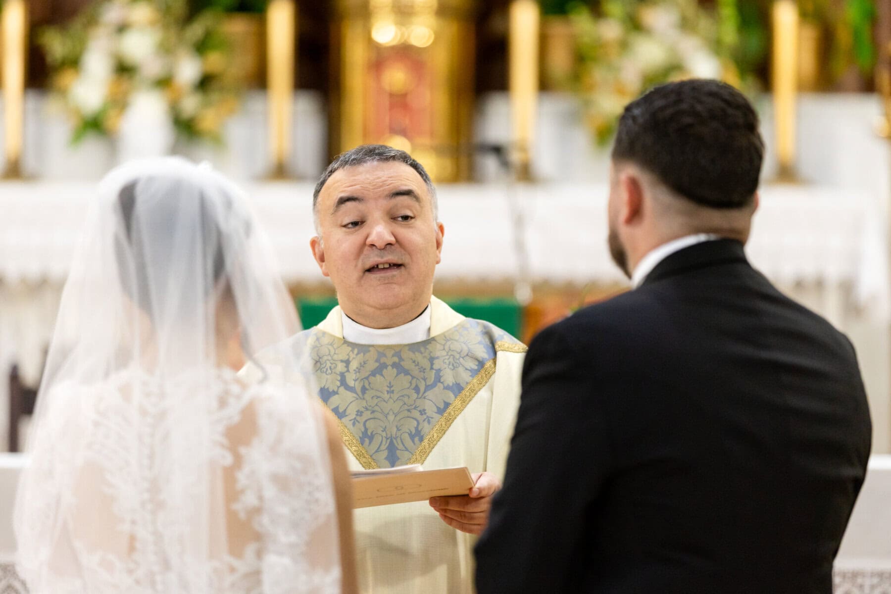 Wedding At Santo Christo Parish in Fall River 39 A priest stands at the altar reading to a bride and groom during their Santo Christo Parish wedding in Fall River.