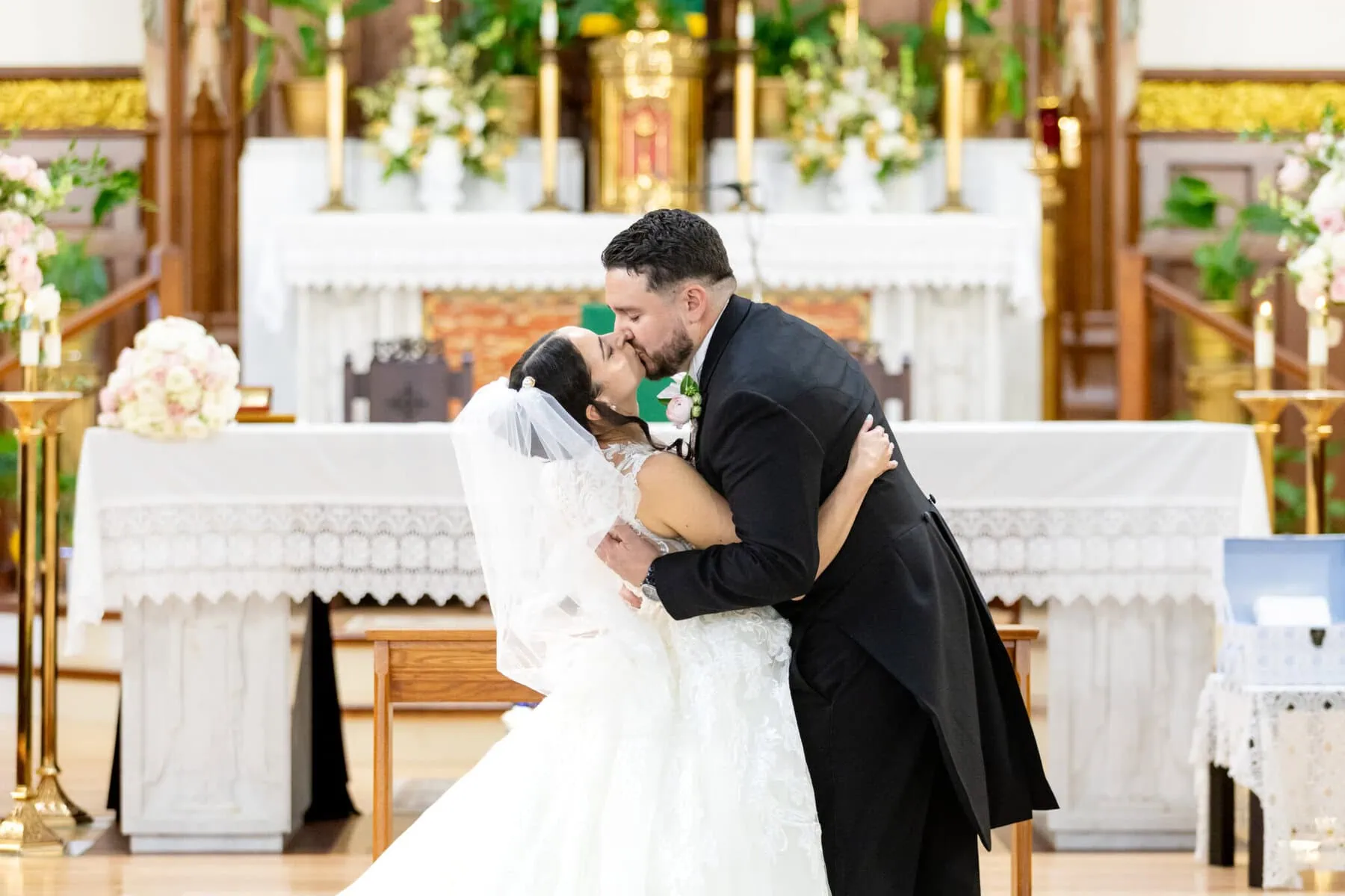 Wedding At Santo Christo Parish in Fall River 46 A bride and groom kiss at the altar during their Fall River wedding at the beautifully decorated Santo Christo Parish.
