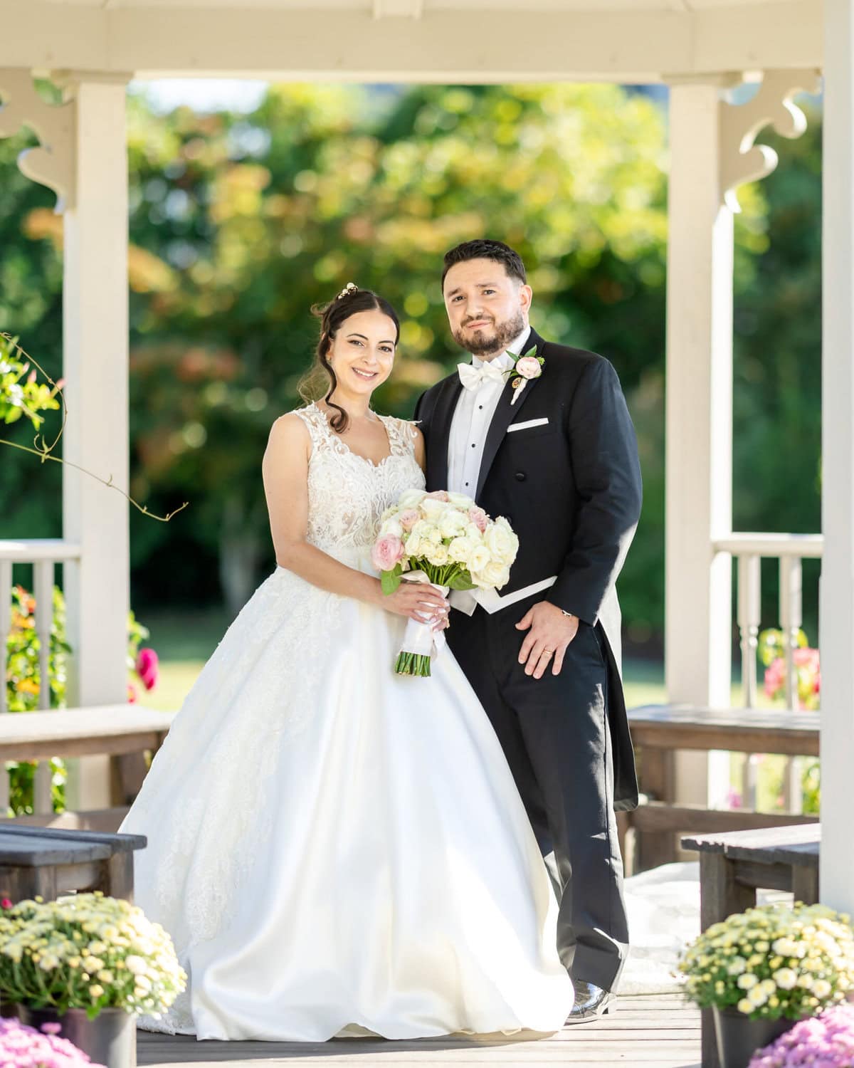 Wedding Photos at Roseland Nursery 4 A bride and groom pose under a gazebo at Roseland Nursery, holding a bouquet for their memorable wedding photos.