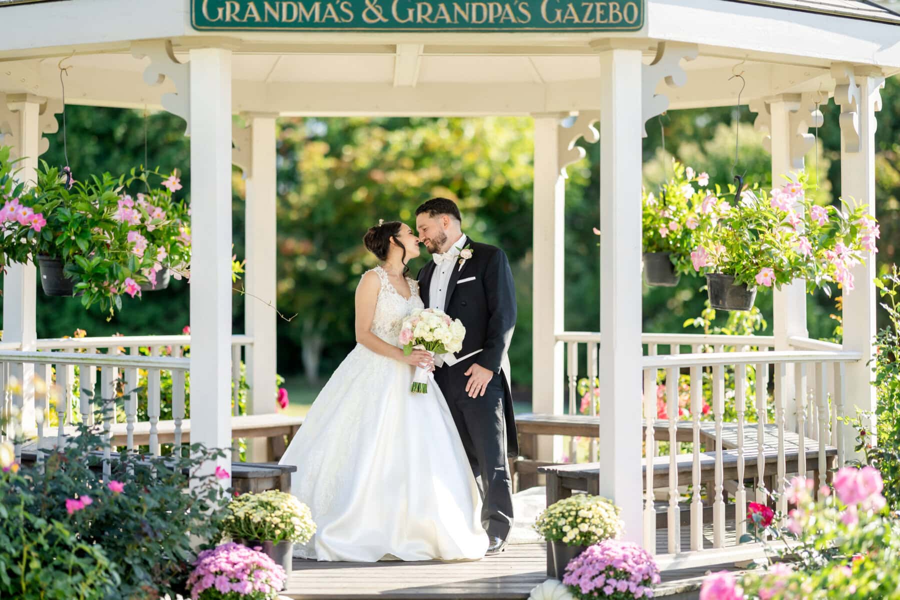 Wedding Photos at Roseland Nursery 9 A bride and groom stand together in a garden gazebo at Roseland Nursery, perfect for memorable wedding photos beneath a charming sign.