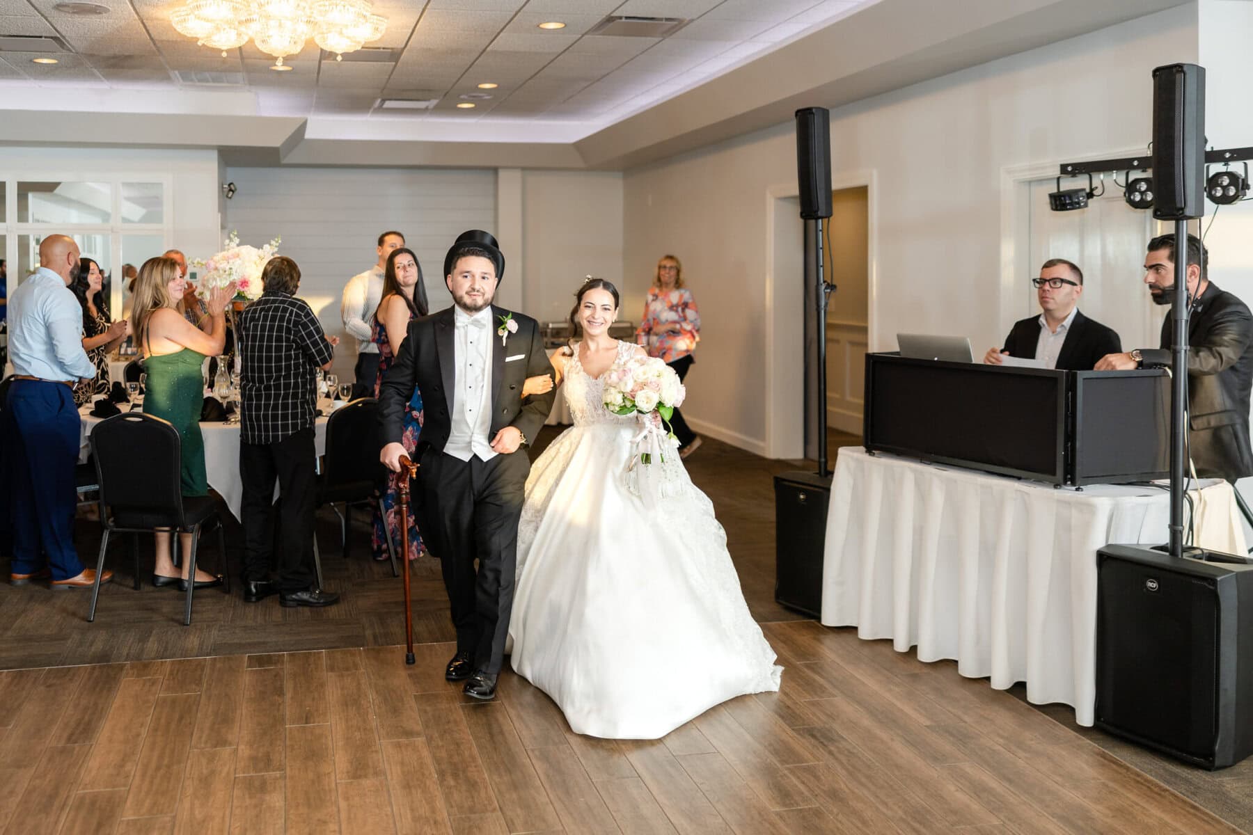 Wedding Reception at The Century House in Acushnet 13 A bride and groom enter their wedding reception at The Century House in Acushnet, as guests watch and a DJ stands by the booth in the background.