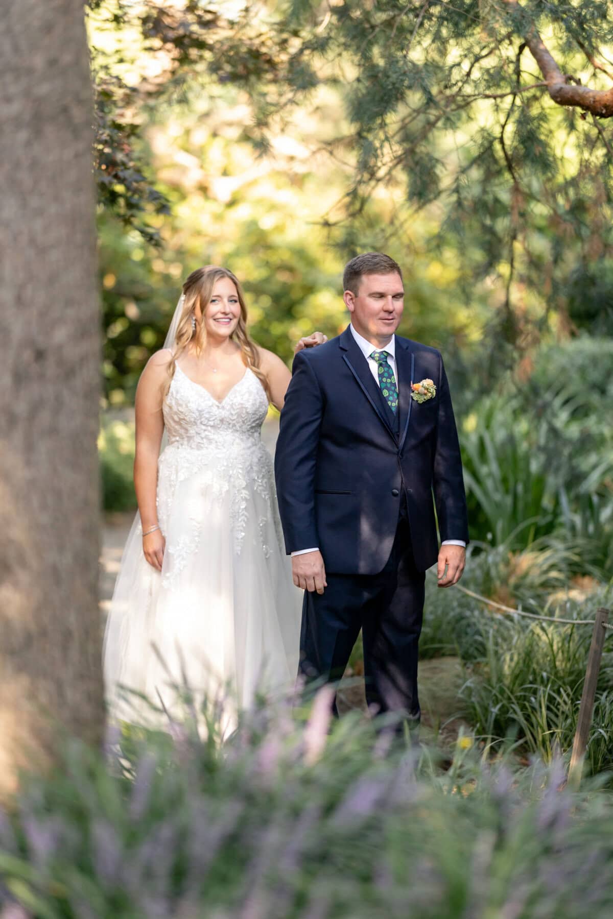 Stunning Wedding at the Roger Williams Botanical Gardens 8 A woman in a white wedding dress stands beside a man in a navy suit at Roger Williams Botanical Gardens.