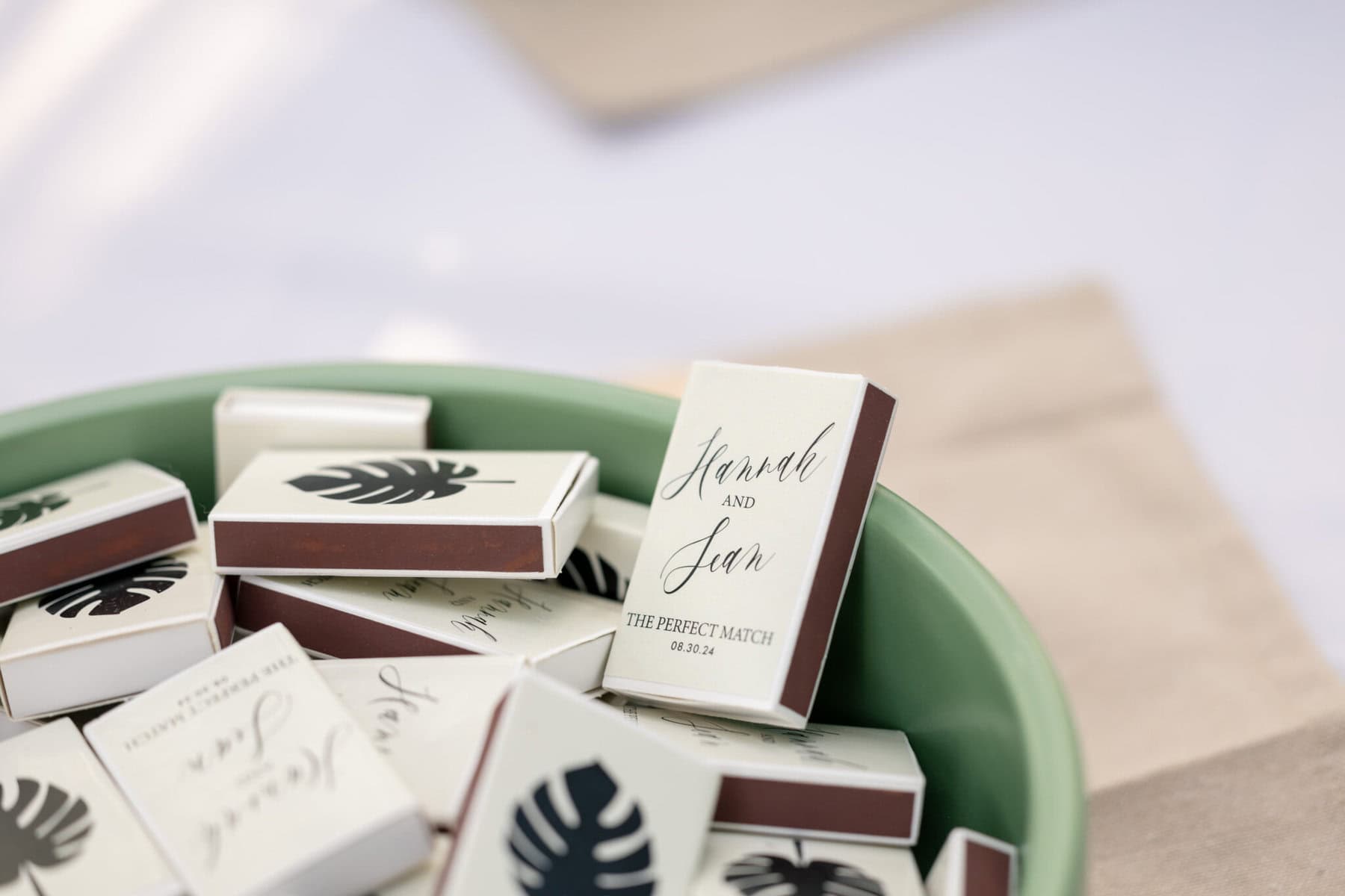 Stunning Wedding at the Roger Williams Botanical Gardens 43 A green bowl of personalized wedding matchboxes labeled "Hannah and Sam," perfect for Roger Williams Botanical Gardens.