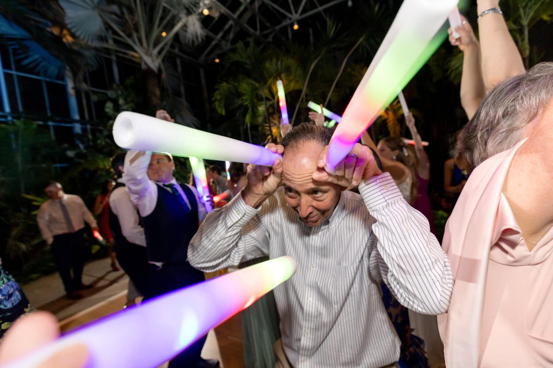 Stunning Wedding at the Roger Williams Botanical Gardens 84 A man holds two glowing light sticks to his head as others dance with lights at a lively wedding in Roger Williams Botanical Gardens.