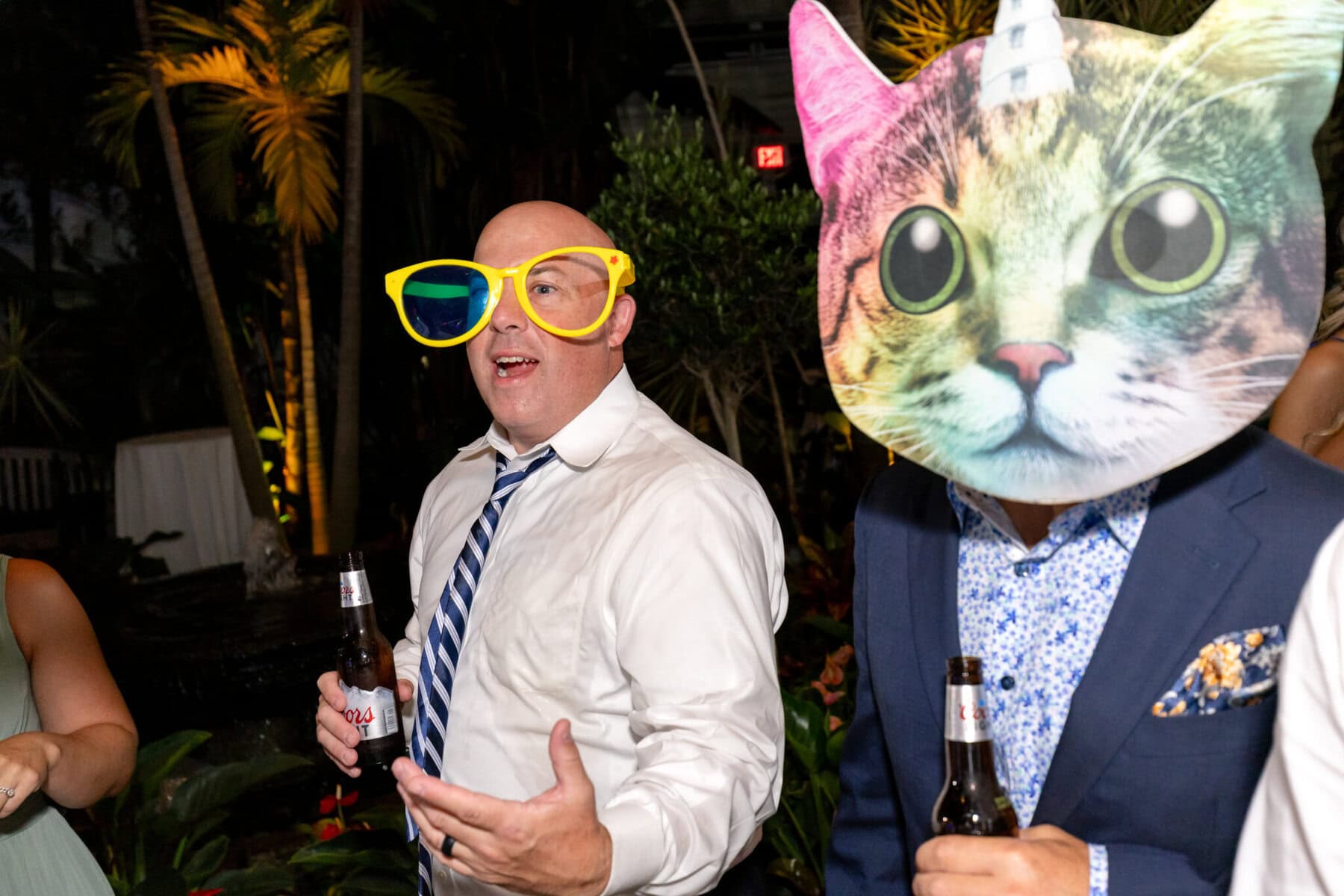 Stunning Wedding at the Roger Williams Botanical Gardens 89 A man in a tie and oversized yellow glasses poses with a cat-masked friend at a wedding party in Roger Williams Botanical Gardens.