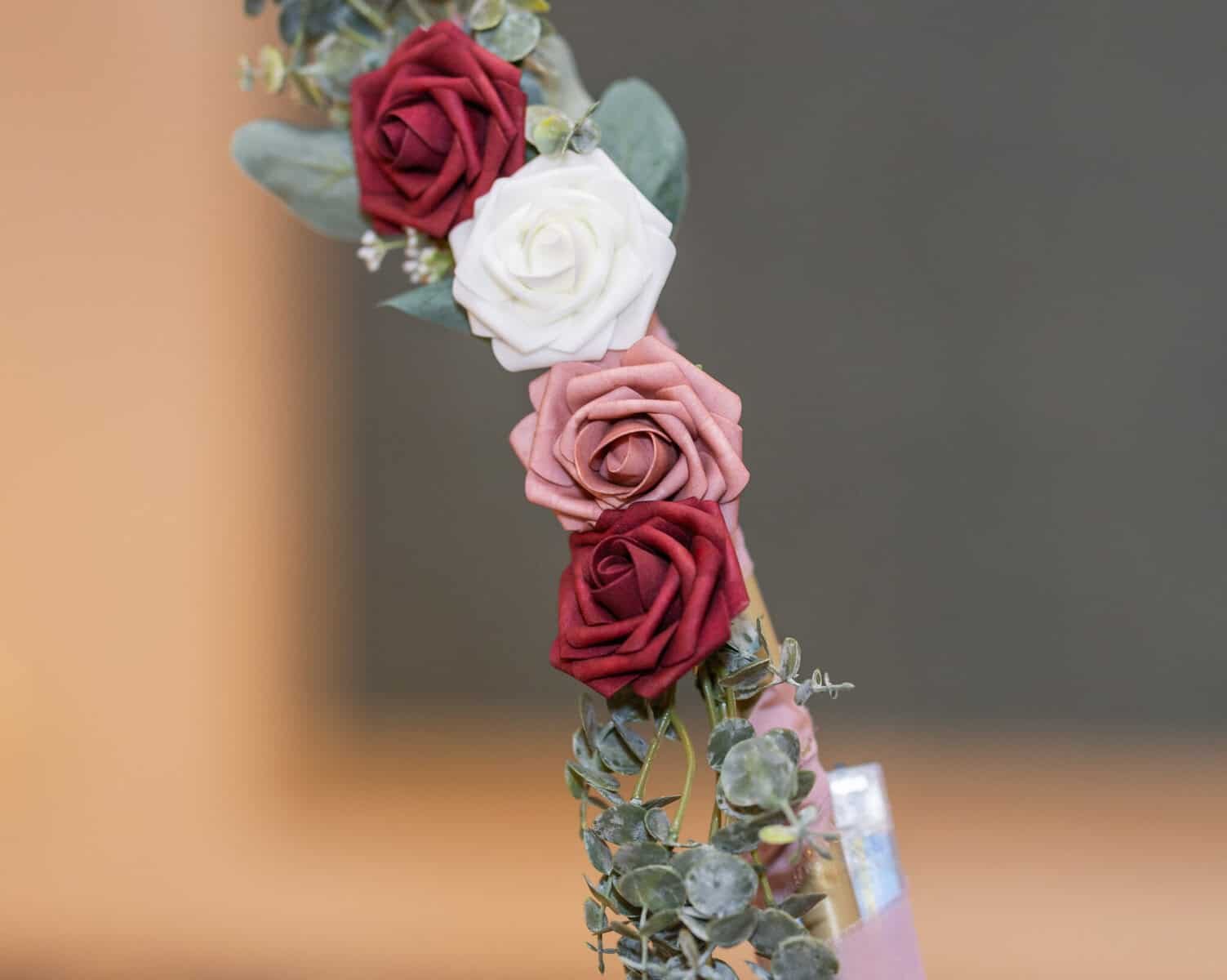 Wedding at the Springfield Elks lodge 54 A close-up of an arrangement featuring two red roses, one pink rose, and one white rose, perfect for a Springfield wedding, surrounded by green foliage against a blurred background.