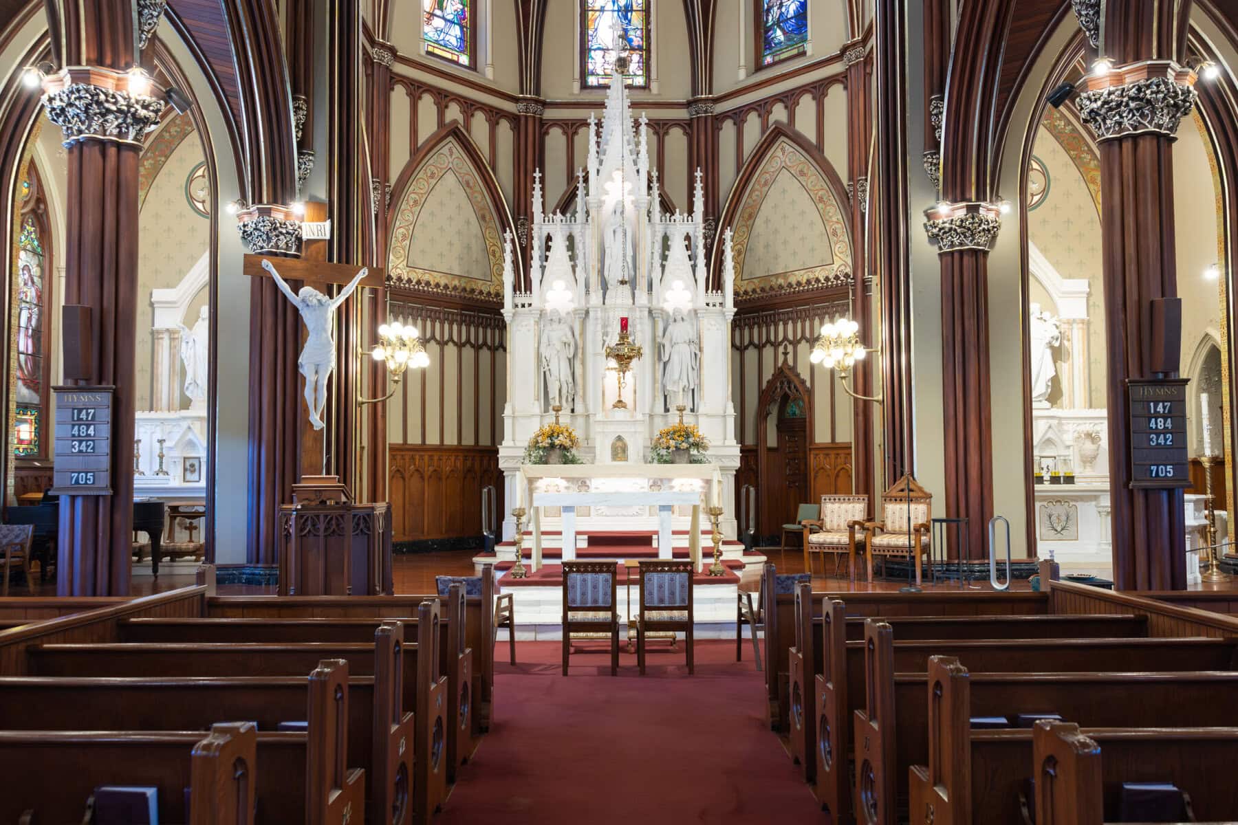 Wedding At St. Mary's Church in North Attleborough 9 Interior of St. Mary's church in North Attleborough with wooden pews, a white altar, statues, stained glass, and tall arched details—perfect for a wedding.