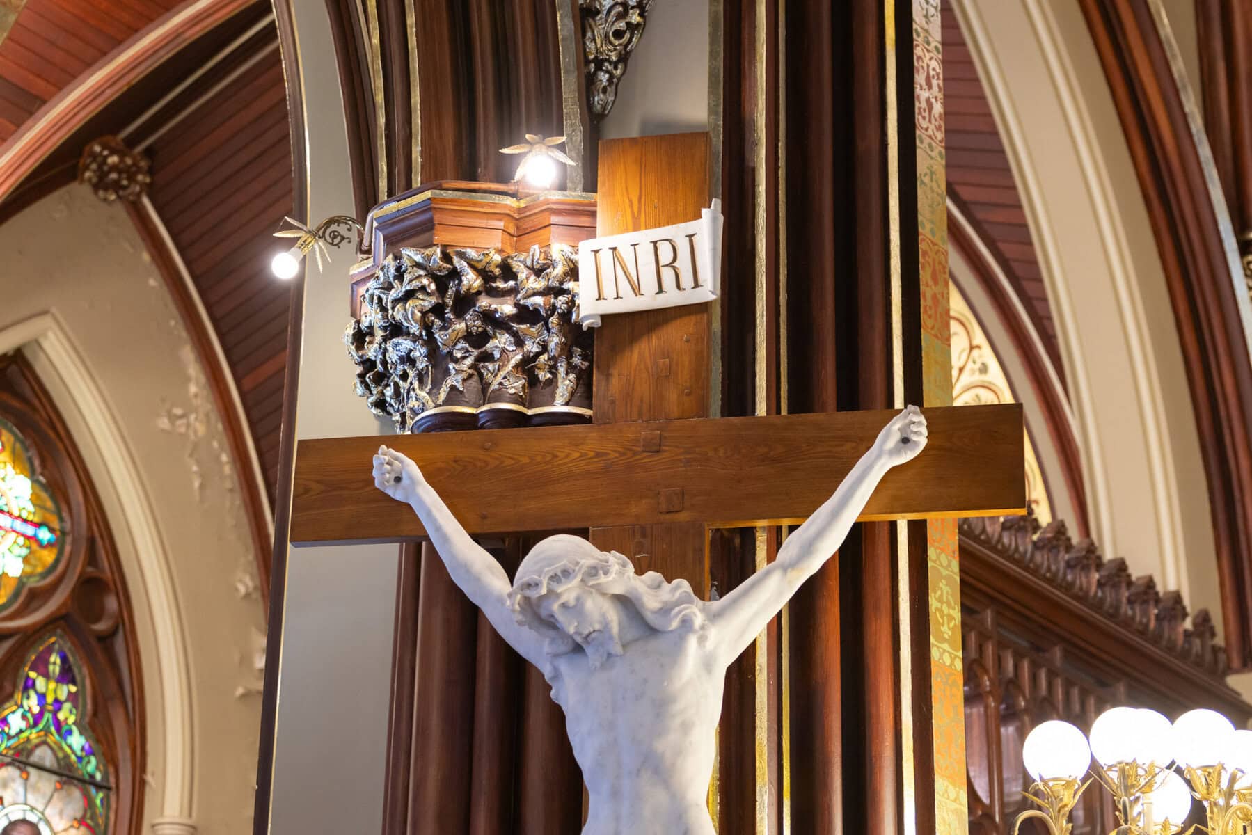 Wedding At St. Mary's Church in North Attleborough 15 A statue of Jesus on the cross with an INRI sign, inside St. Mary's Church in North Attleborough, with ornate columns and stained glass windows.