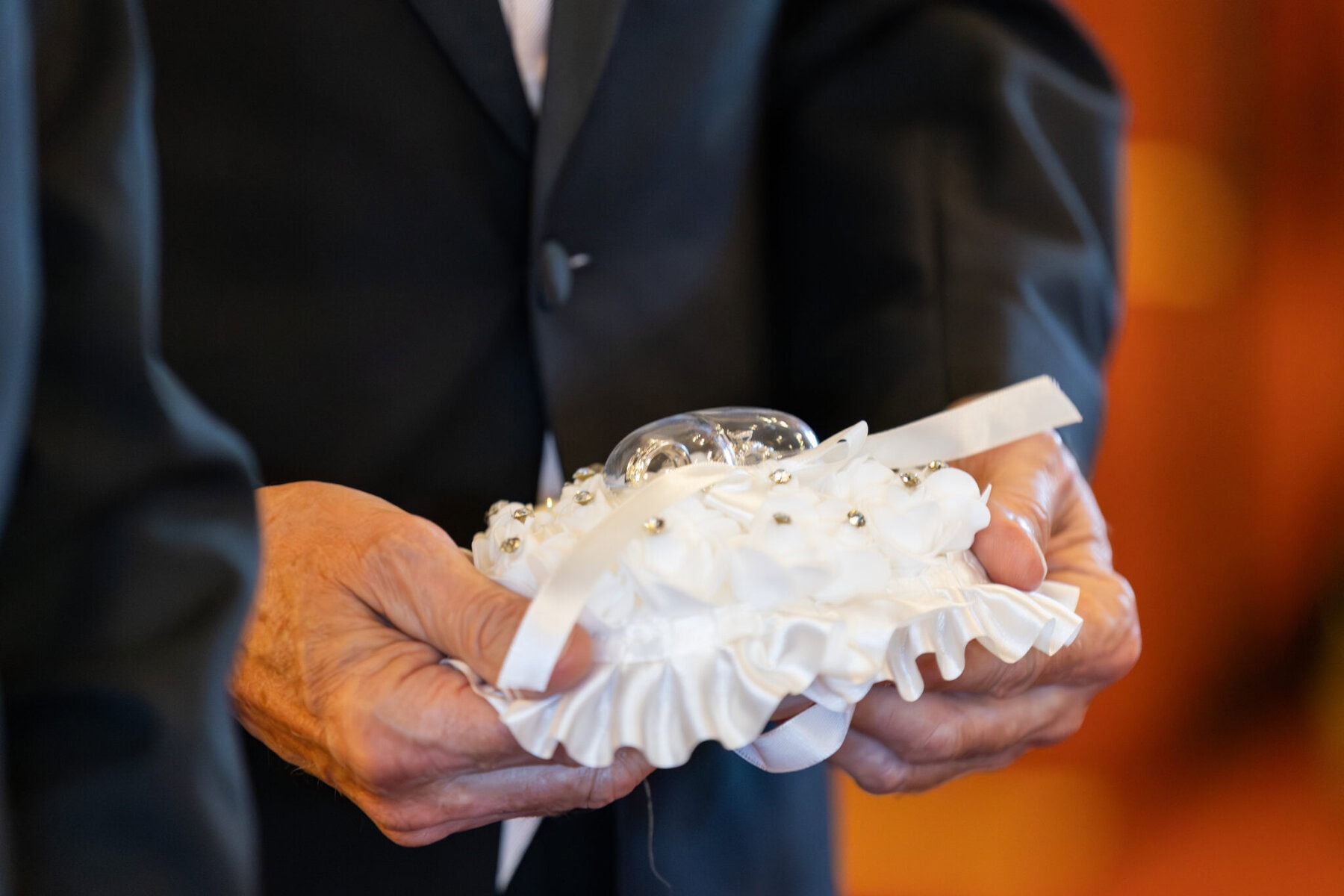 Wedding At St. Mary's Church in North Attleborough 25 At a wedding in North Attleborough, a suited person holds a satin pillow with ribbon and glass heart, likely at St. Mary’s Church.