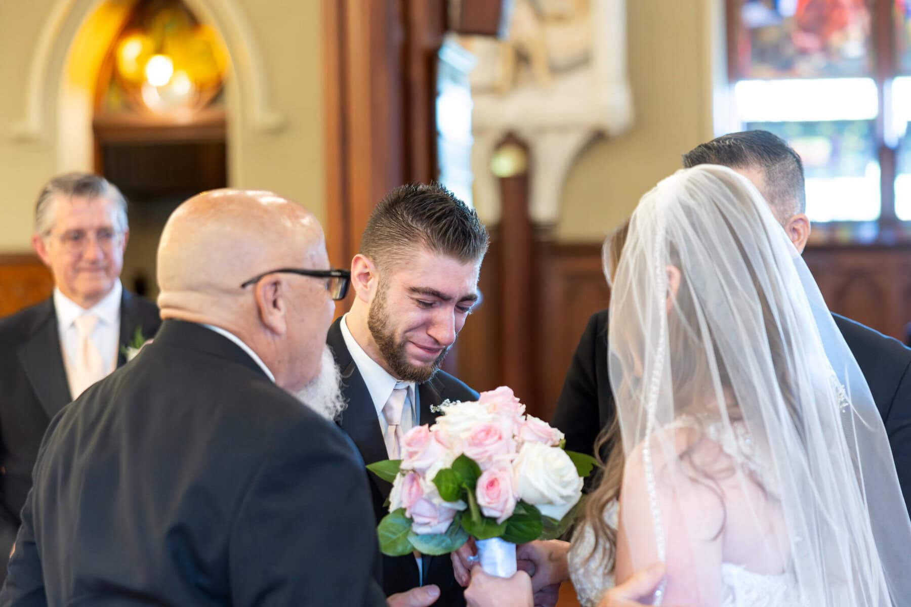 Wedding At St. Mary's Church in North Attleborough 29 A groom is emotional as he meets his bride with a bouquet during their wedding at St. Mary's church, with guests watching in North Attleborough.