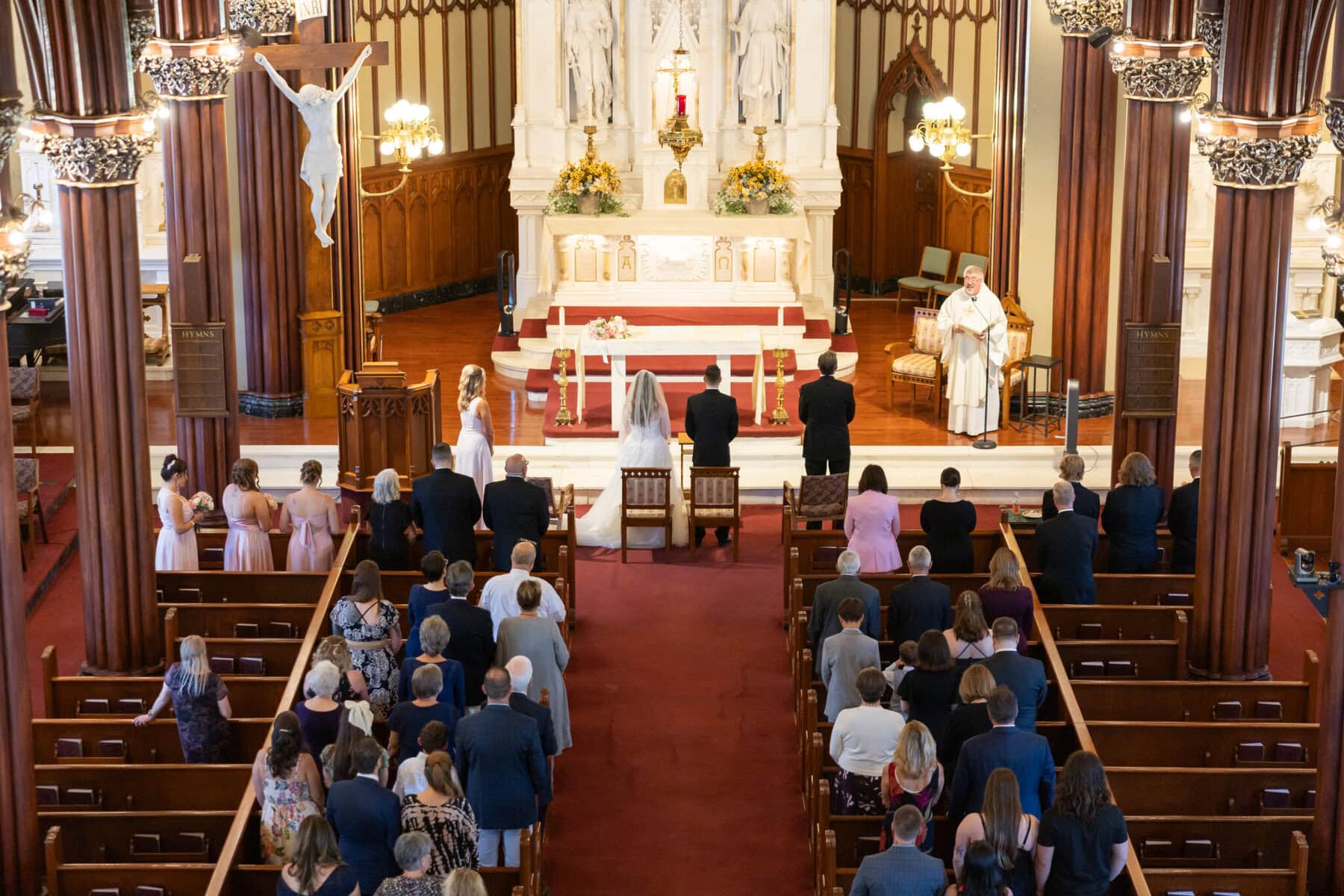 Wedding At St. Mary's Church in North Attleborough 45 A wedding ceremony unfolds at St. Mary's Church in North Attleborough, with guests seated and a priest officiating as the couple stands at the altar.