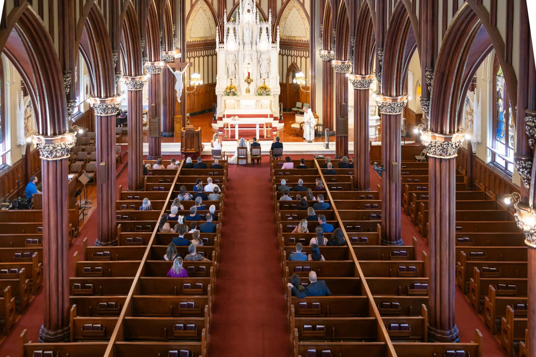 Wedding At St. Mary's Church in North Attleborough 44 A church interior at St. Mary's Church in North Attleborough with people in pews facing an ornate altar, viewed from the back center aisle.