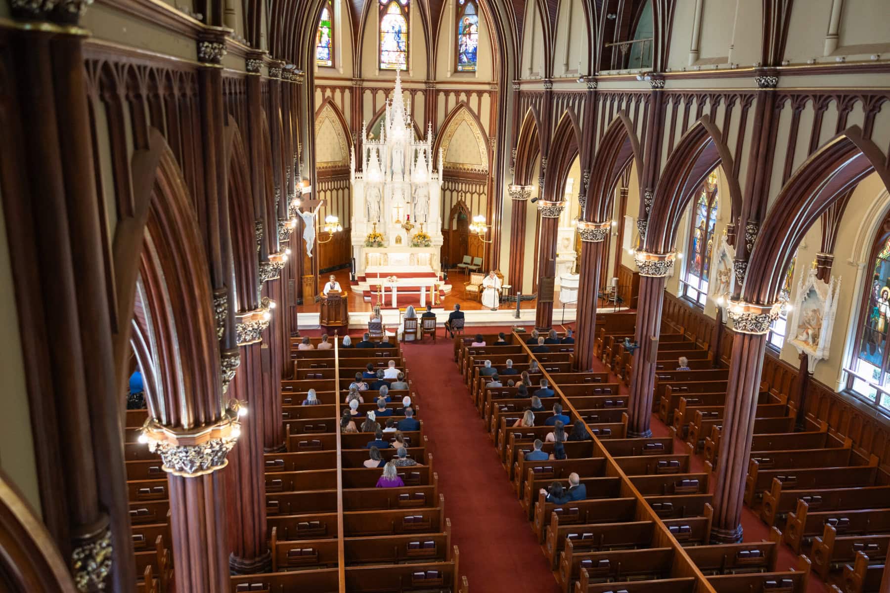 Wedding At St. Mary's Church in North Attleborough 46 A view inside St. Mary's Church, North Attleborough, with people in pews facing the altar, tall arches, and stained glass—perfect for a wedding.