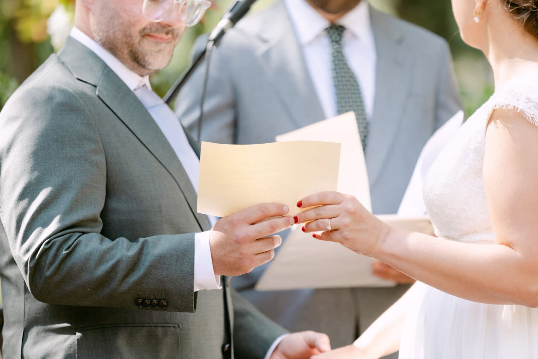 A Worcester Wedding at Cook Pond 33 A man and woman in formal attire hold papers during a Worcester Wedding ceremony, with an officiant standing behind them.